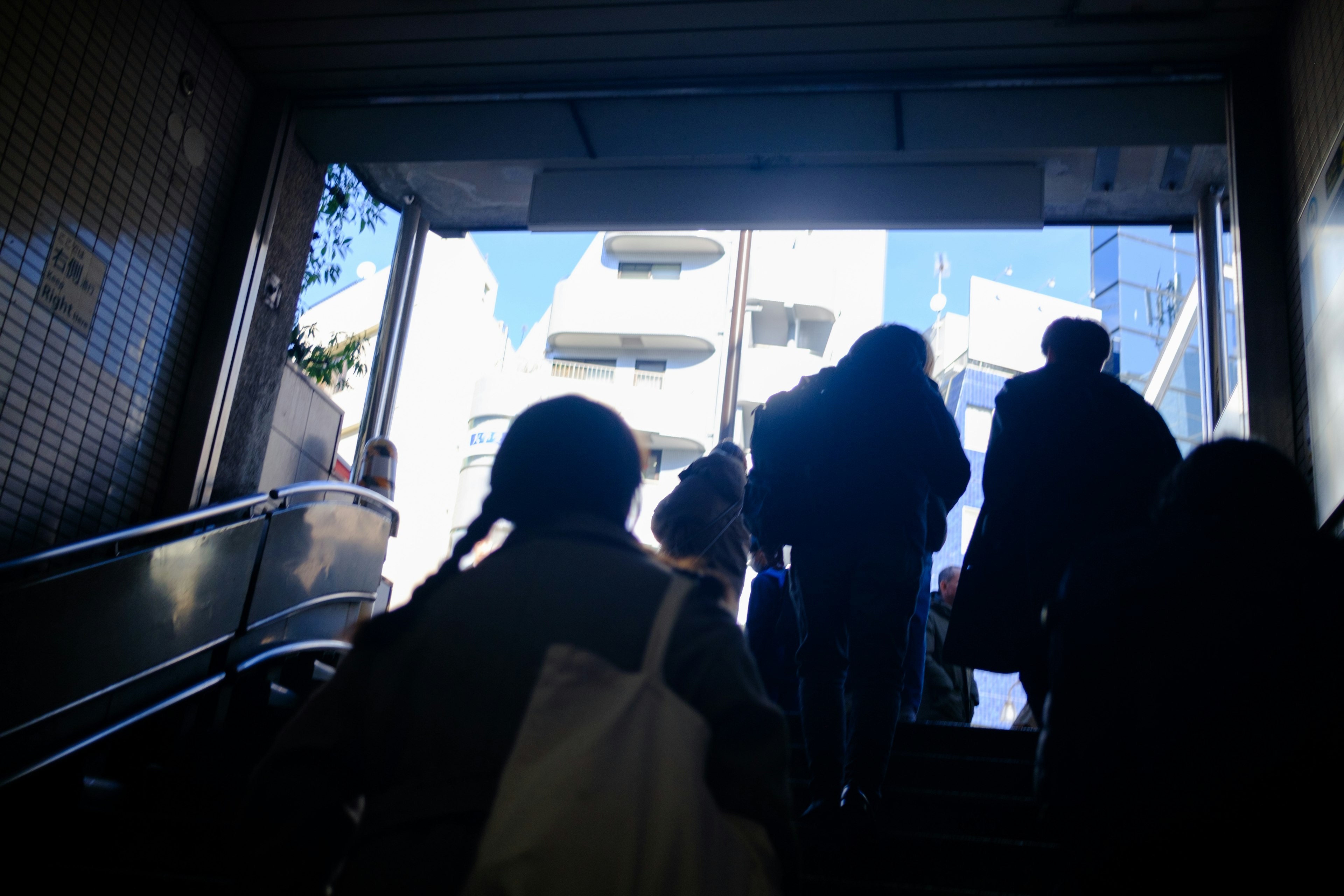 Silhouettes de personnes montant des escaliers avec une lumière vive en arrière-plan