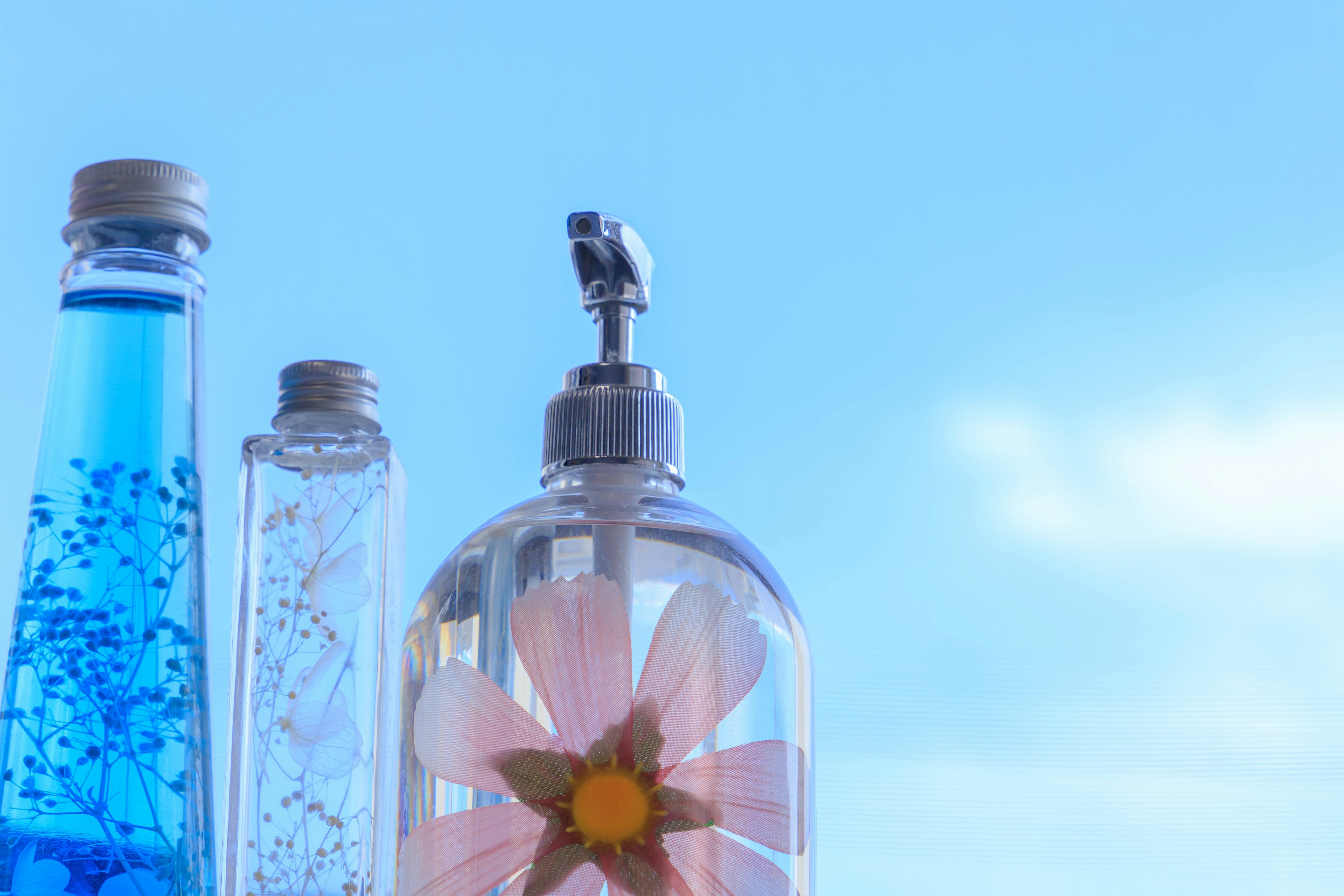 Bottles with colorful liquids and a flower design against a blue background