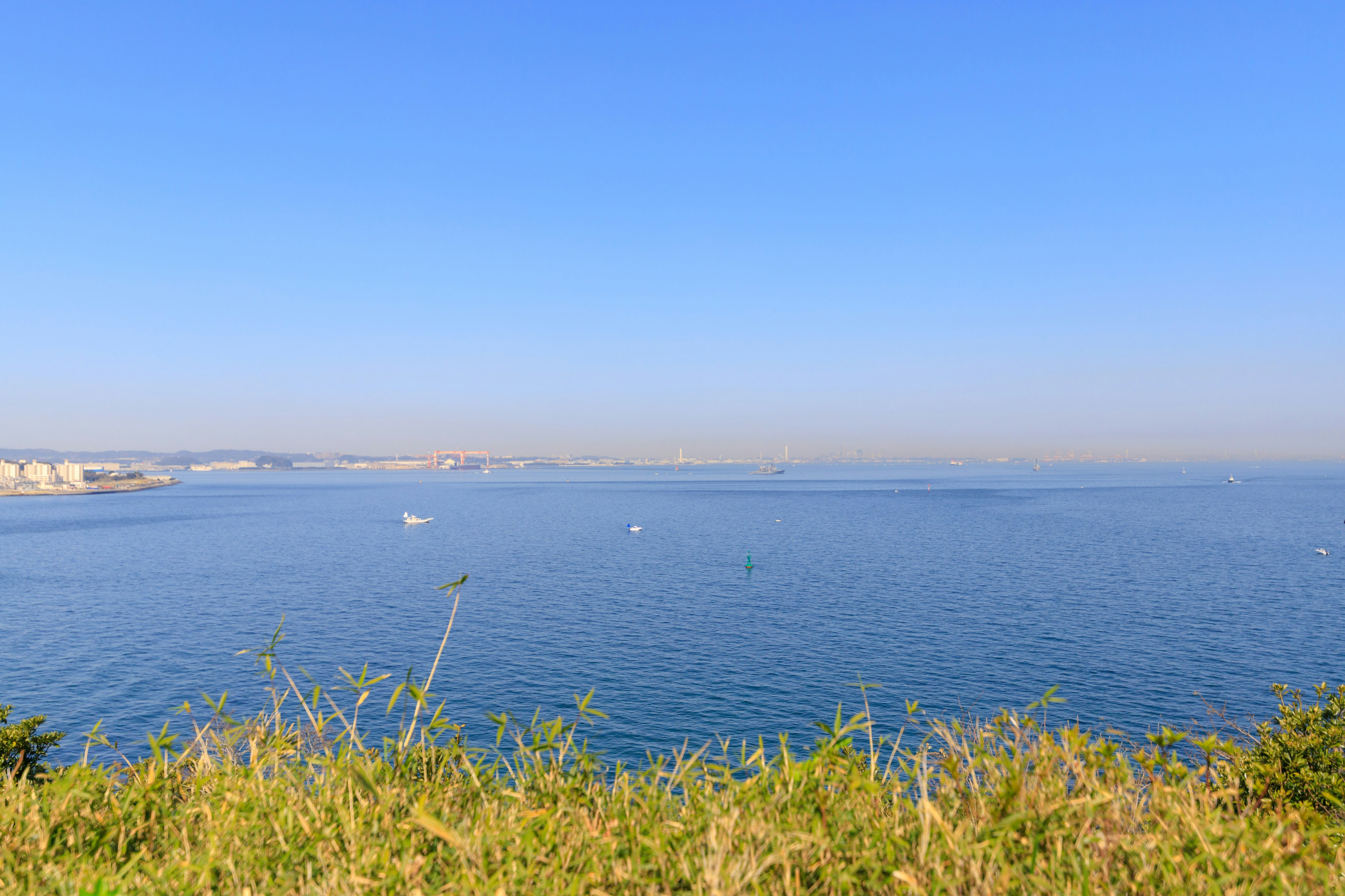 Scenic view of blue sea and sky from a grassy hill