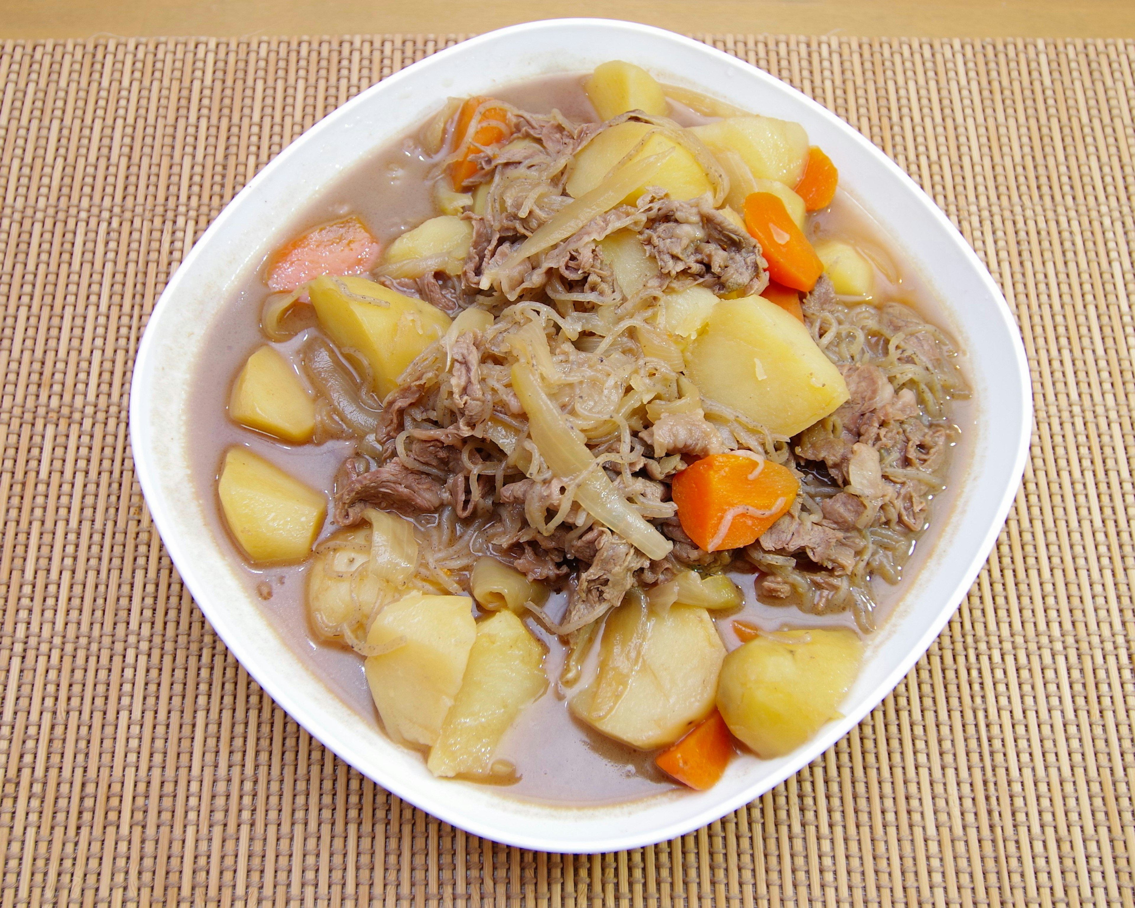 Un bol de ragoût de viande et de légumes copieux servi dans un plat blanc