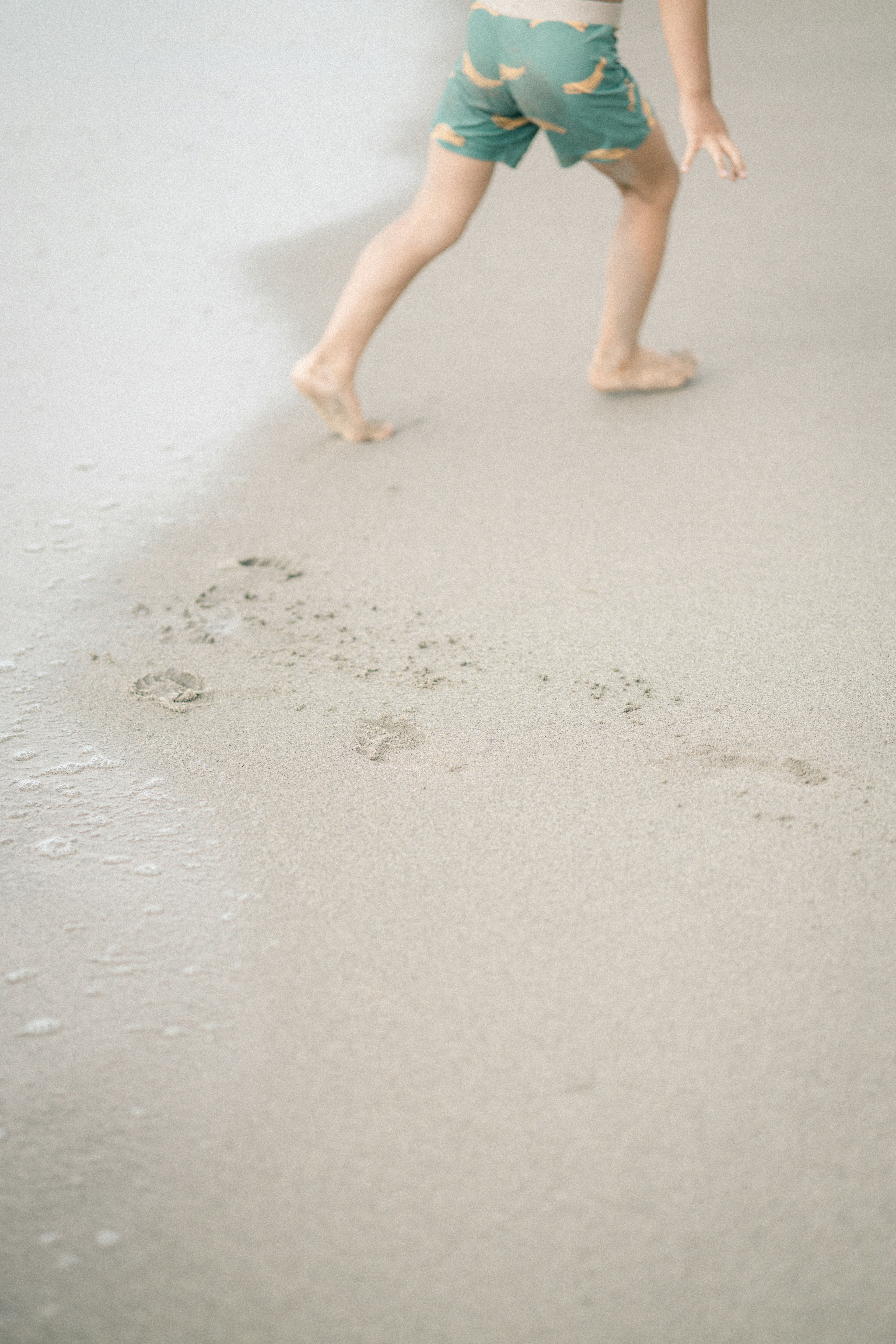 Child walking on the beach leaving footprints in the sand