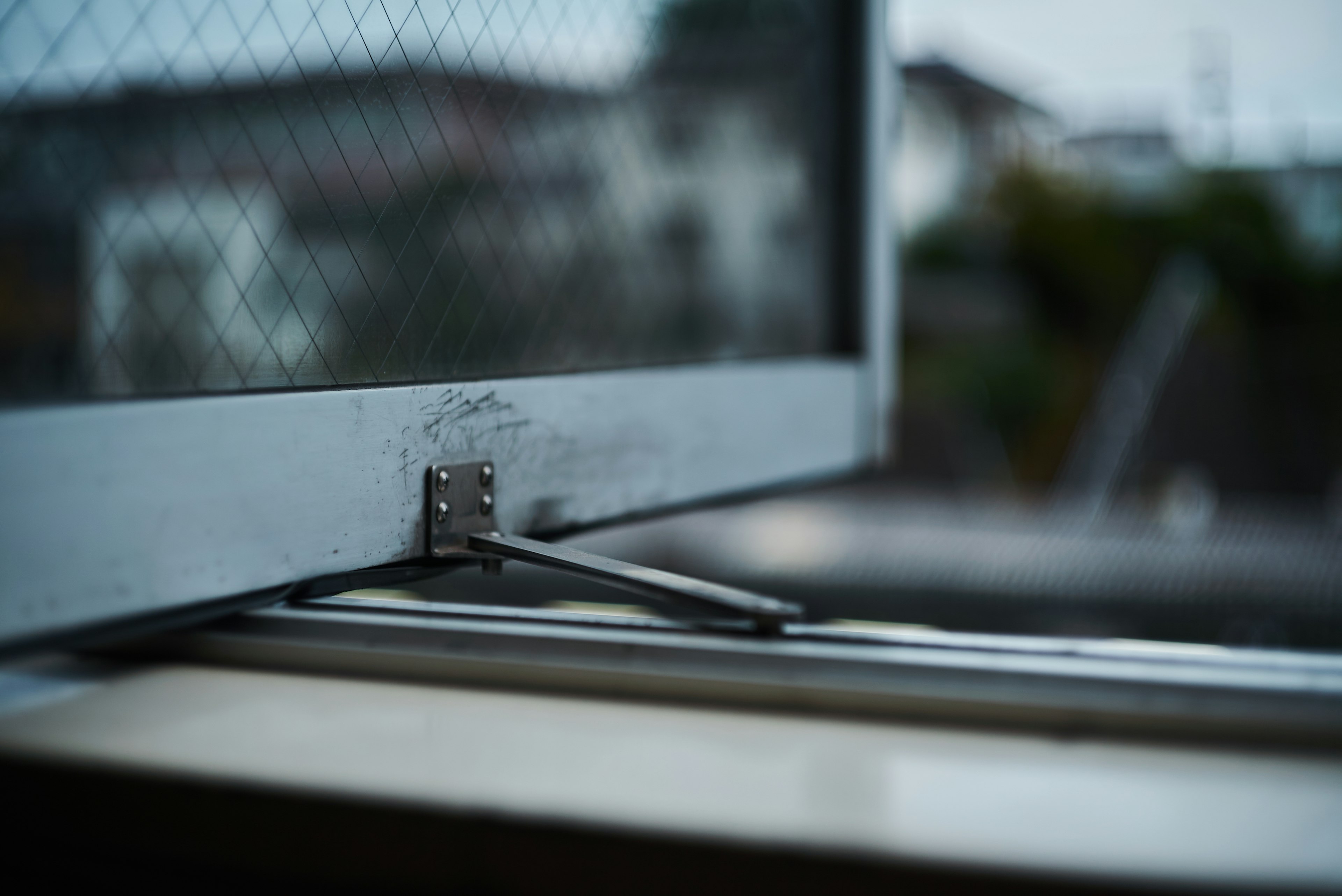 Close-up of window hardware and mesh screen Steel hinge and mesh panel Blurred vibrant background scenery