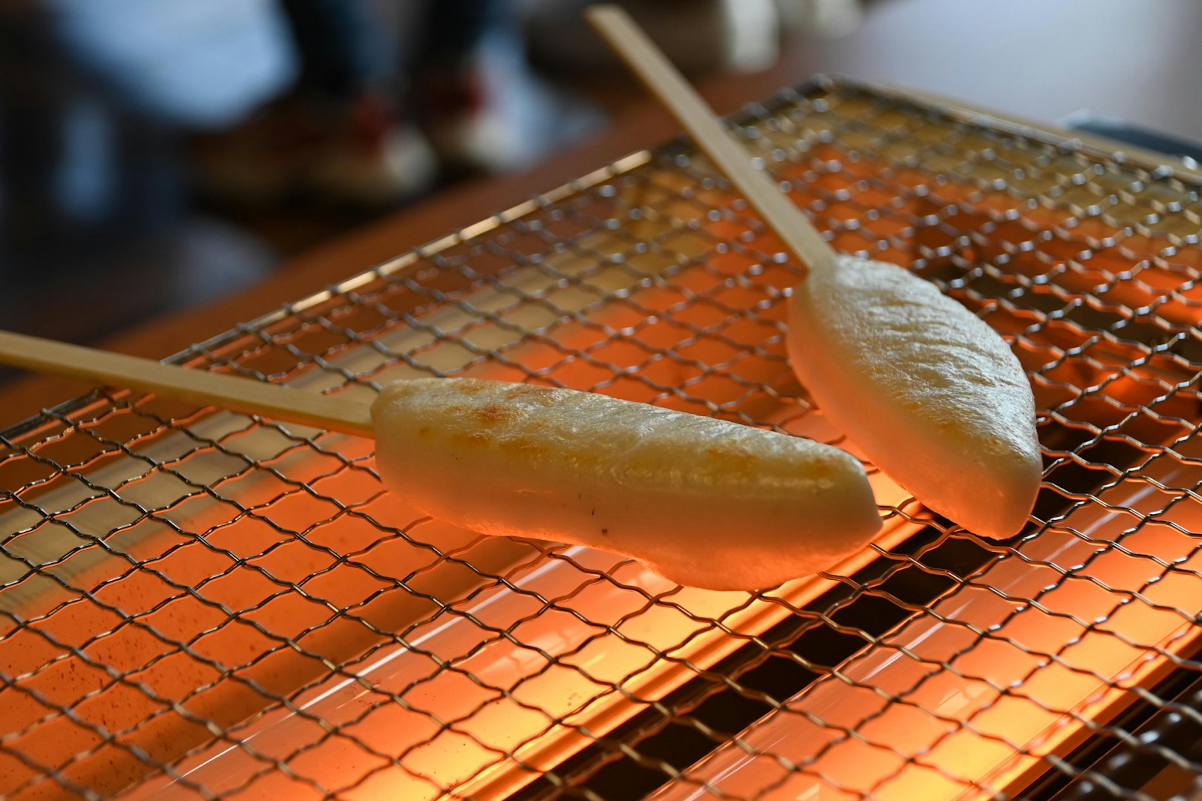 Deux brochettes de gâteaux de riz blancs en train de griller