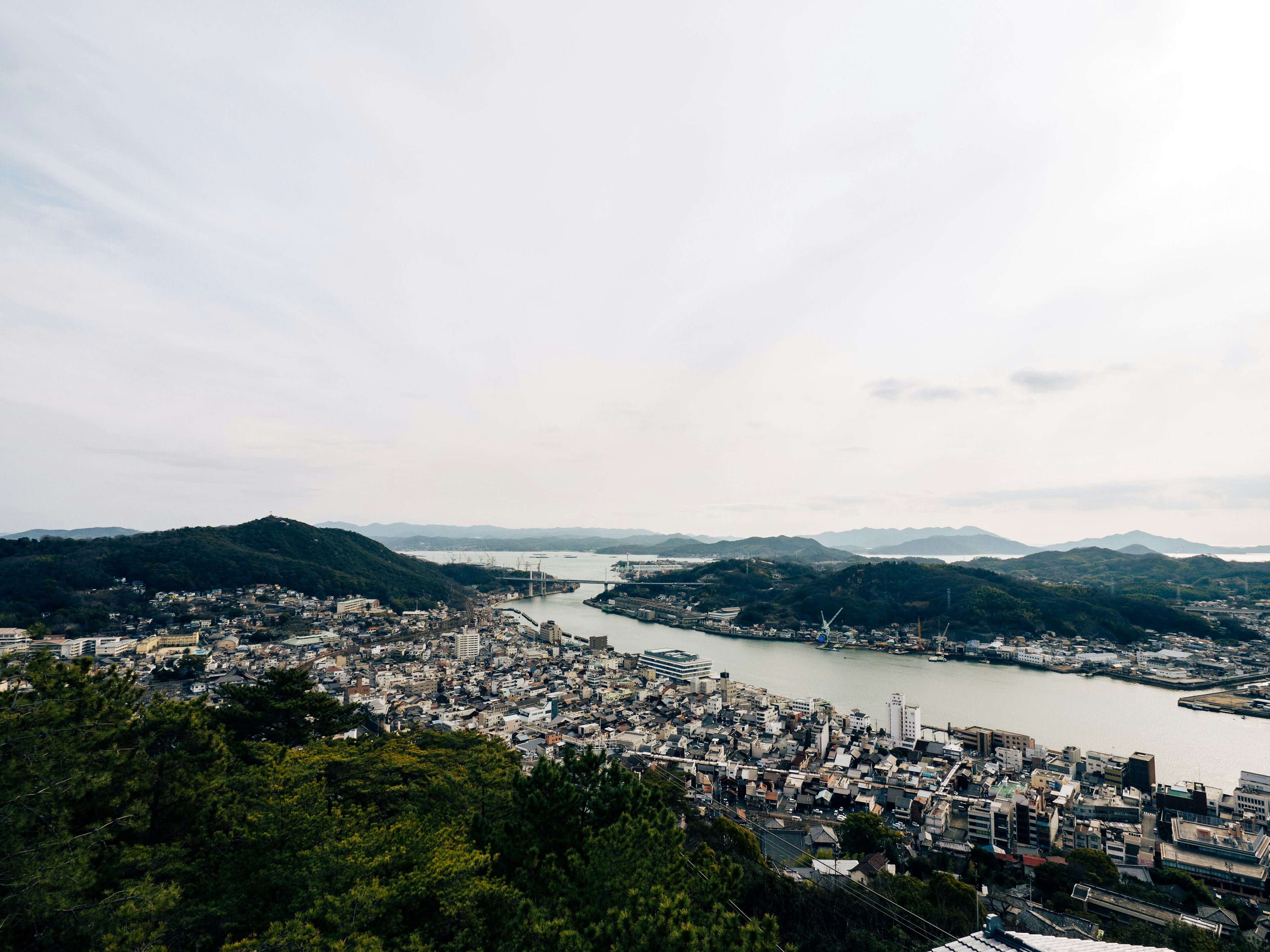 Vista panorámica de Nagasaki que muestra colinas y un río serpenteante