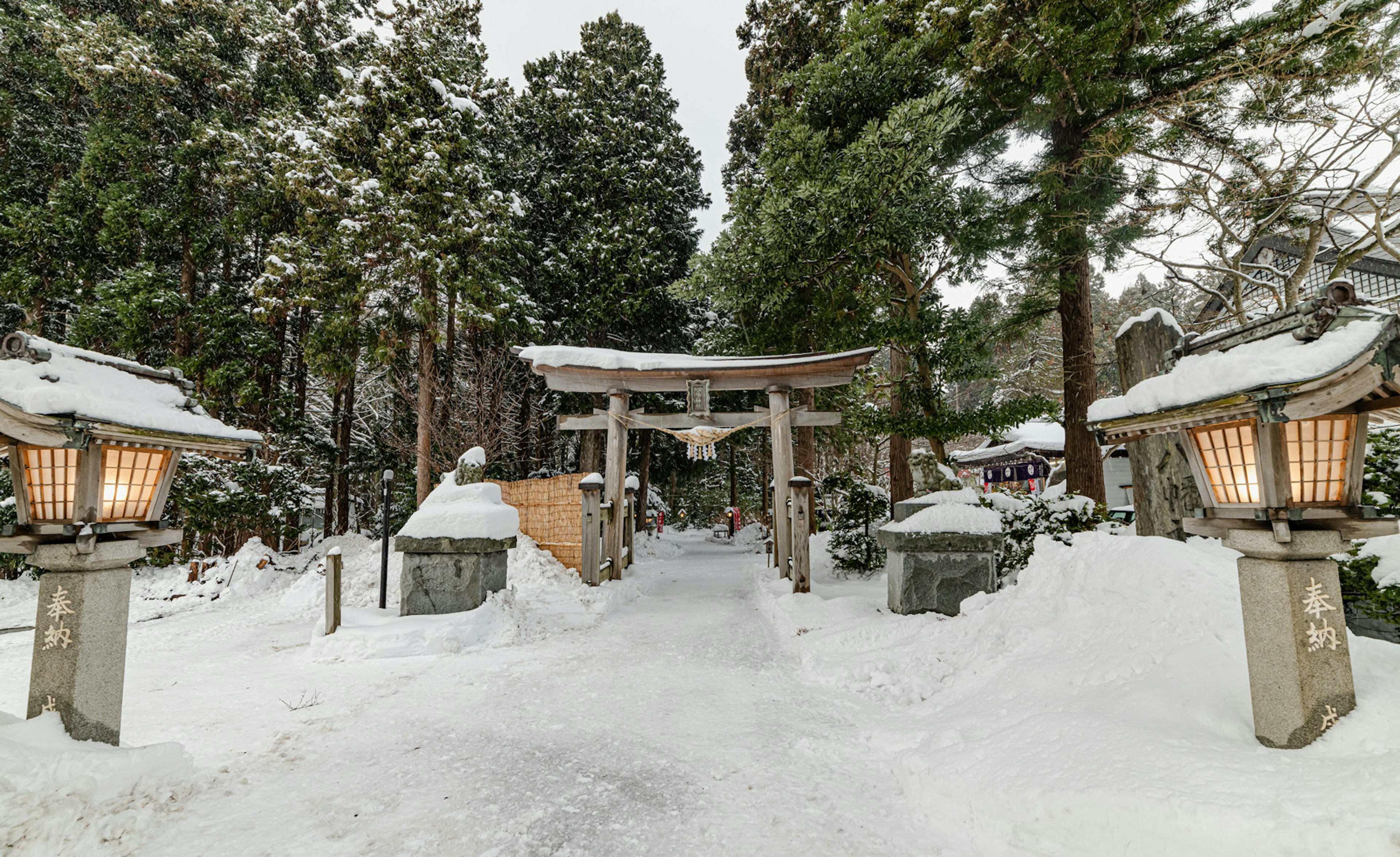 Puerta torii y faroles en un entorno forestal nevado