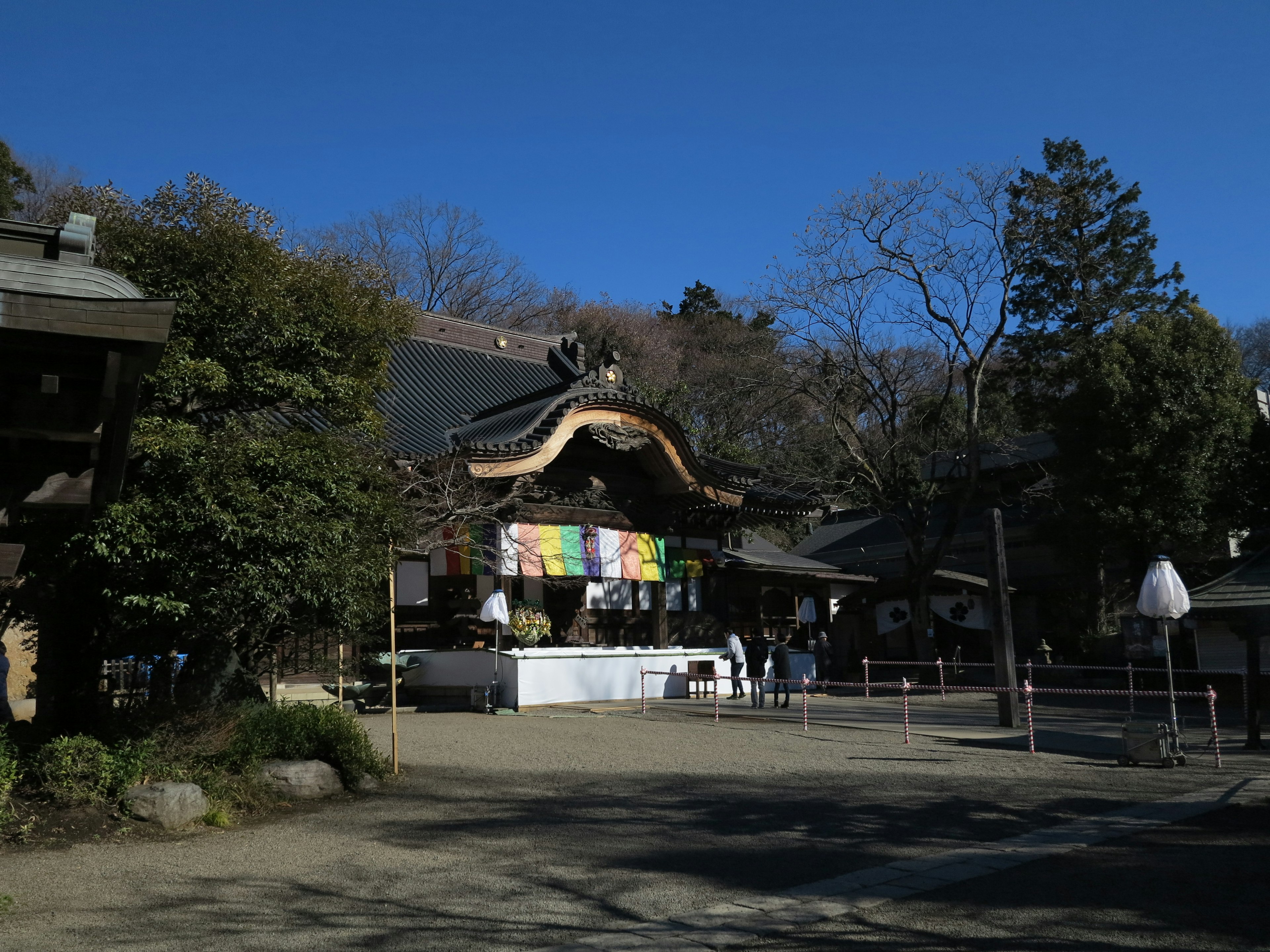 青空の下に広がる神社の風景 様々な色の幕が飾られた社殿 緑の木々に囲まれた静かな場所