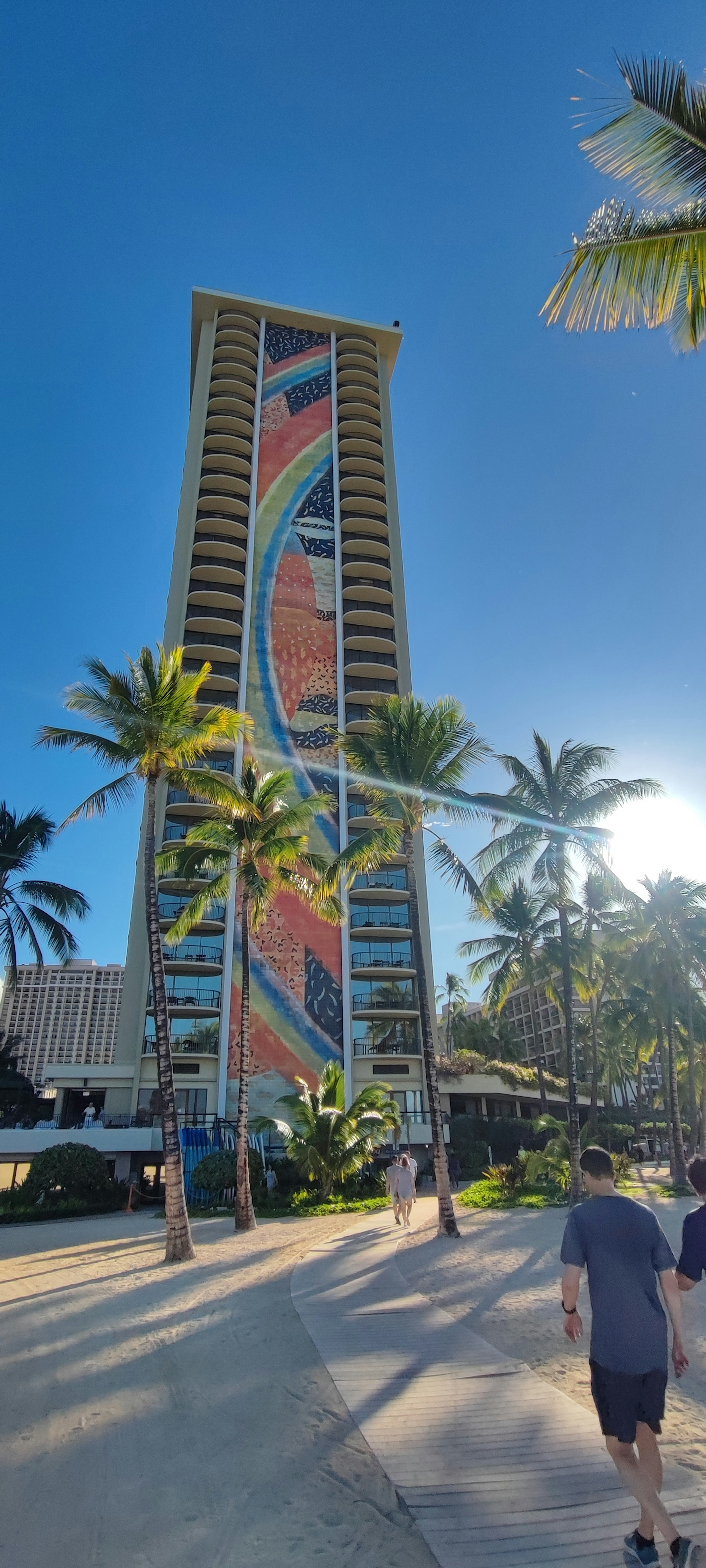 Fachada colorida de un edificio alto con palmeras