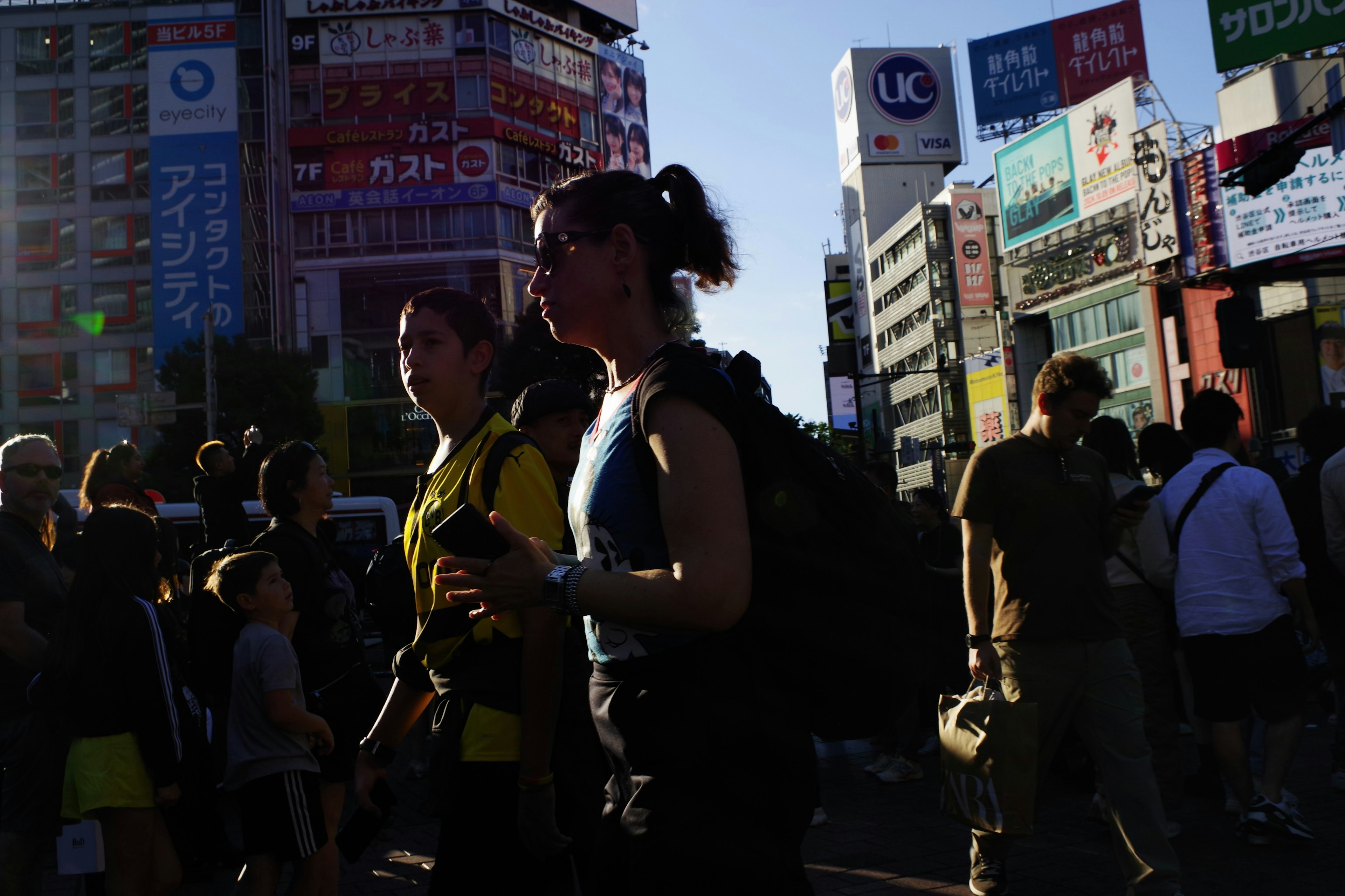 Silhouette di persone che camminano in un'area urbana affollata con edifici