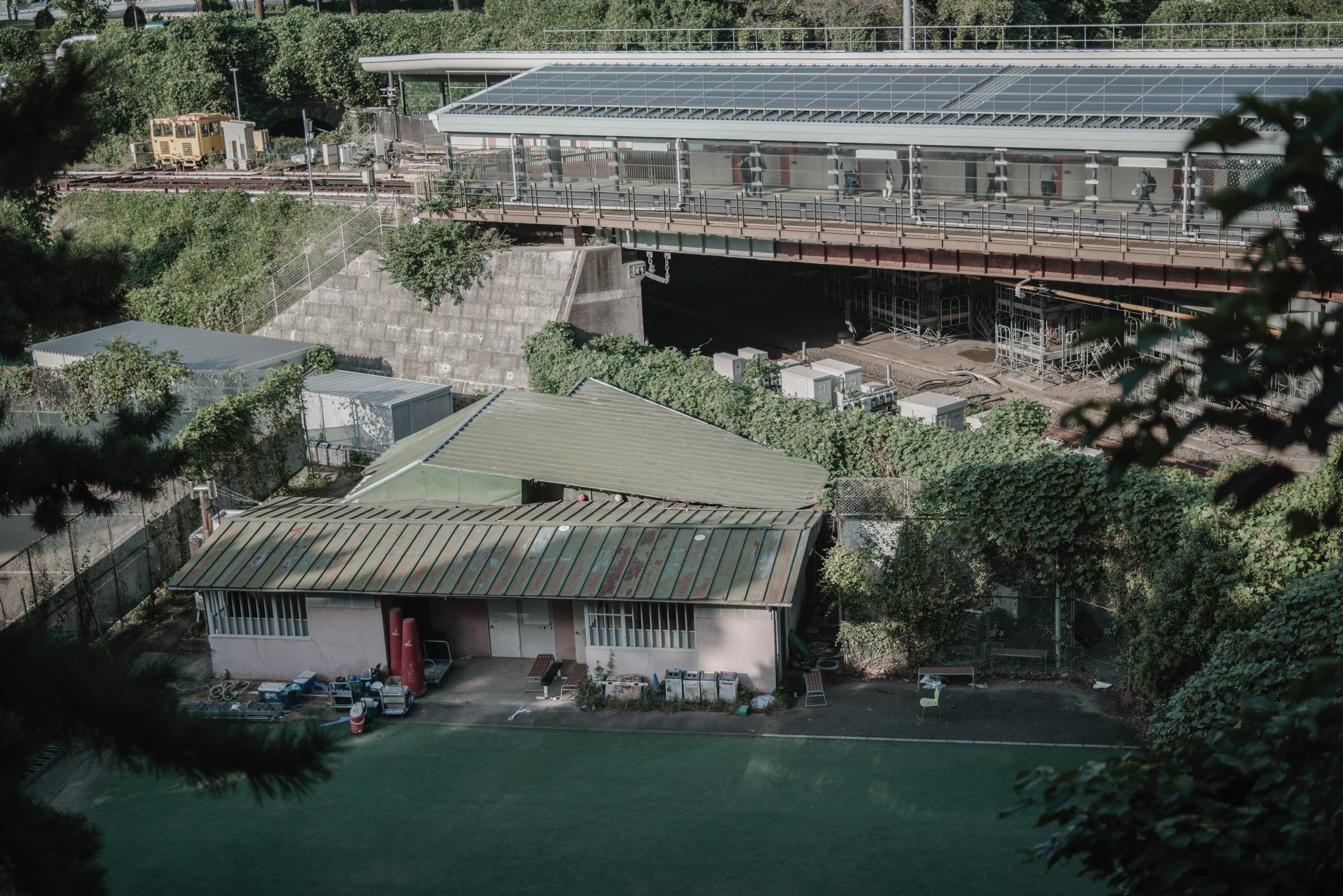 A view of a house with a green roof and a nearby railway station