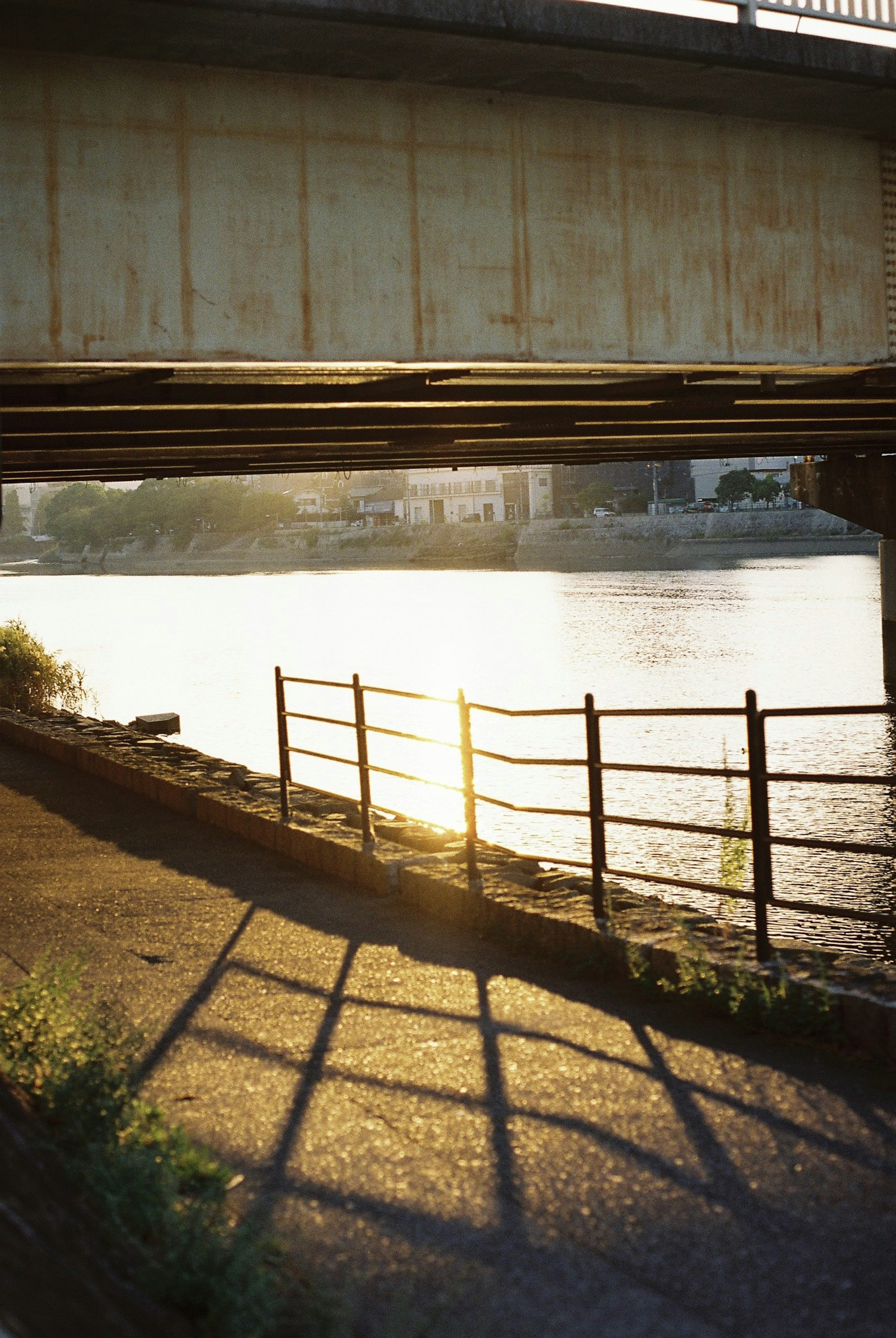 Ponte che proietta ombre sul fiume con riflesso del tramonto