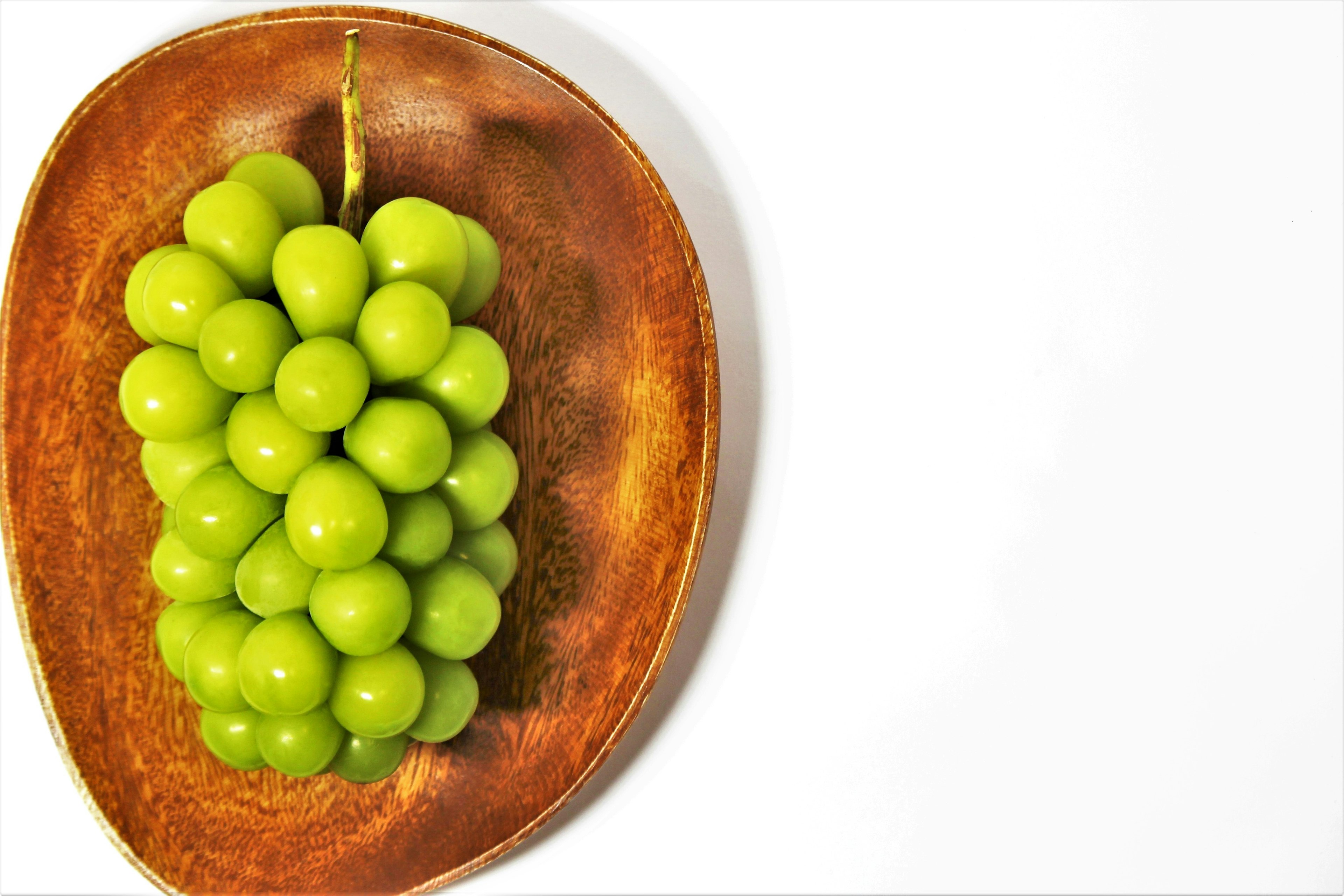 Green grapes arranged on a wooden plate