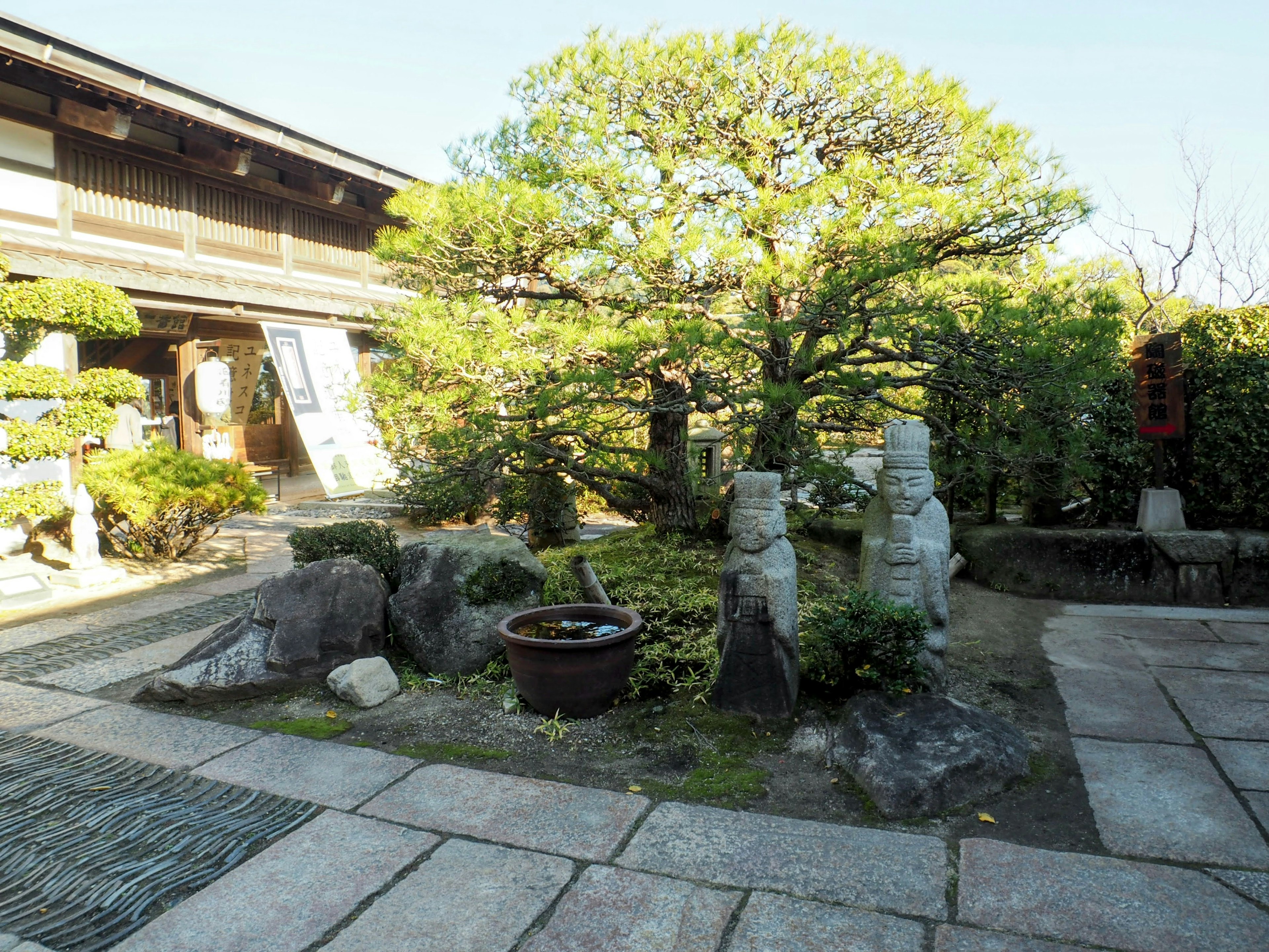 传统日本庭园场景，石雕和郁郁葱葱的绿树