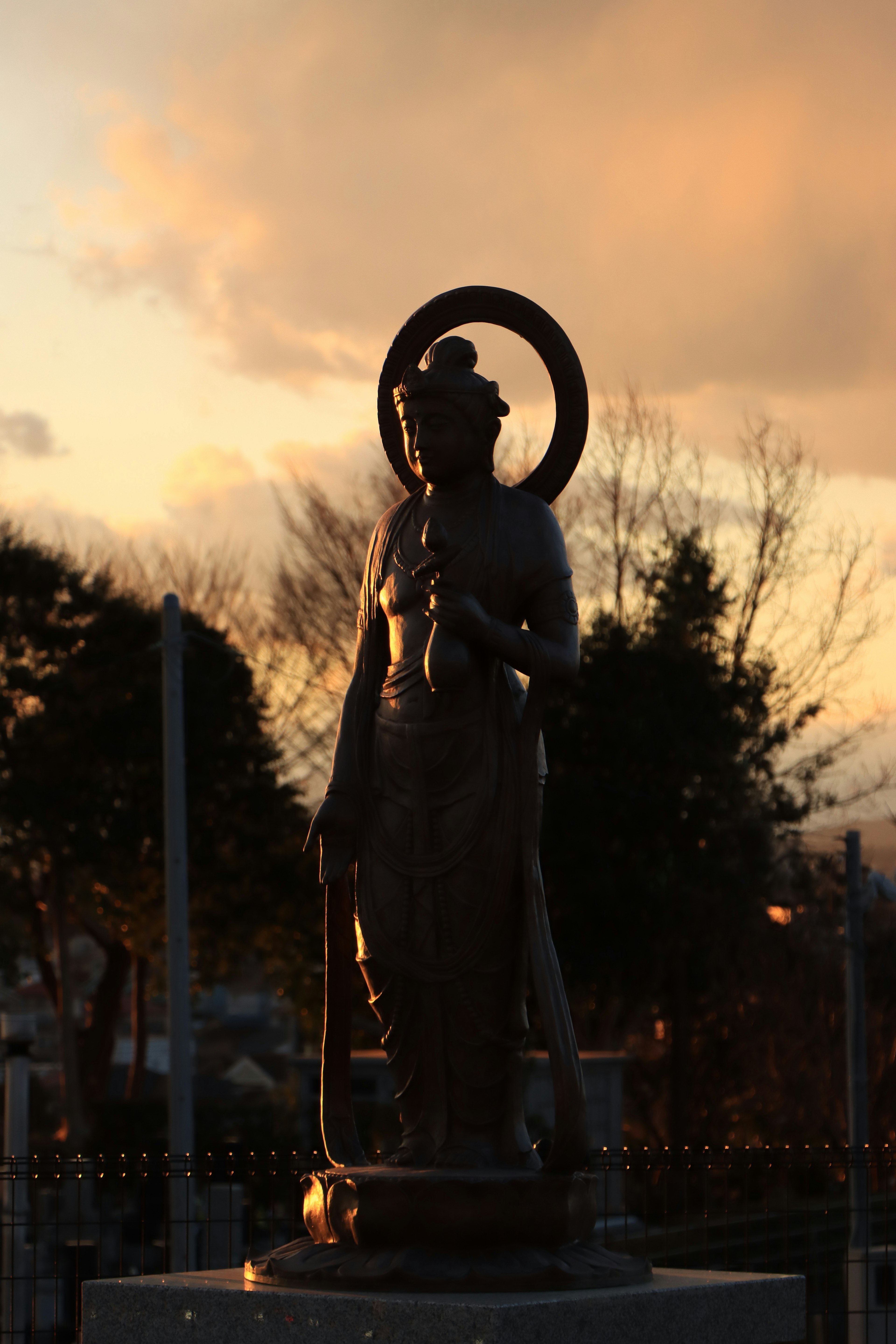 Silhouette of a statue against a sunset backdrop