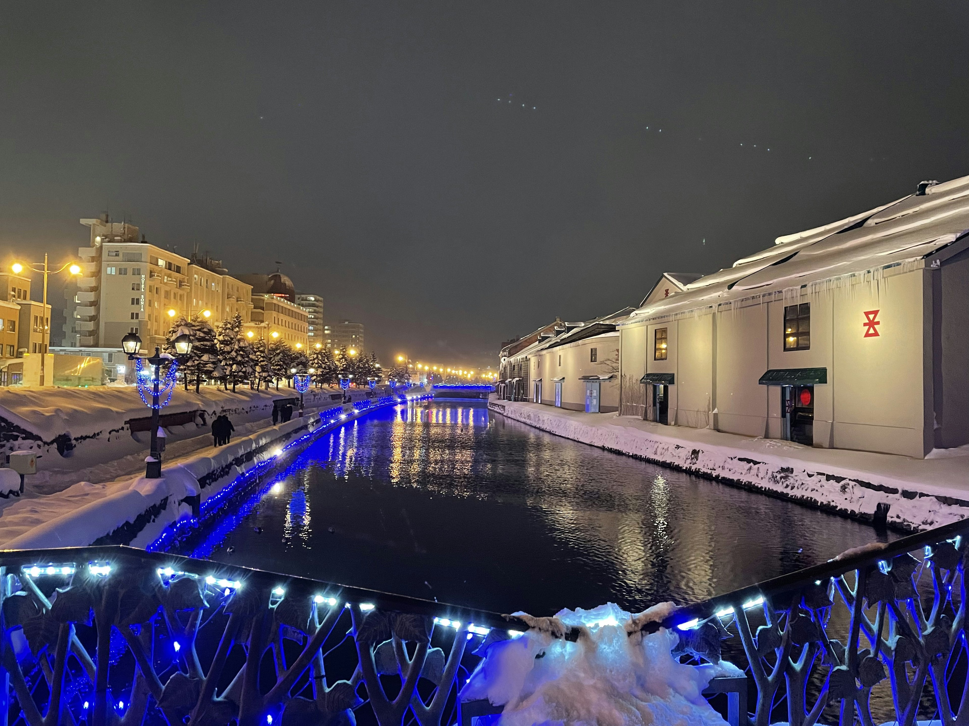 Eine schöne Winterlandschaft mit einem schneebedeckten Fluss und Stadtlichtern in der Nacht