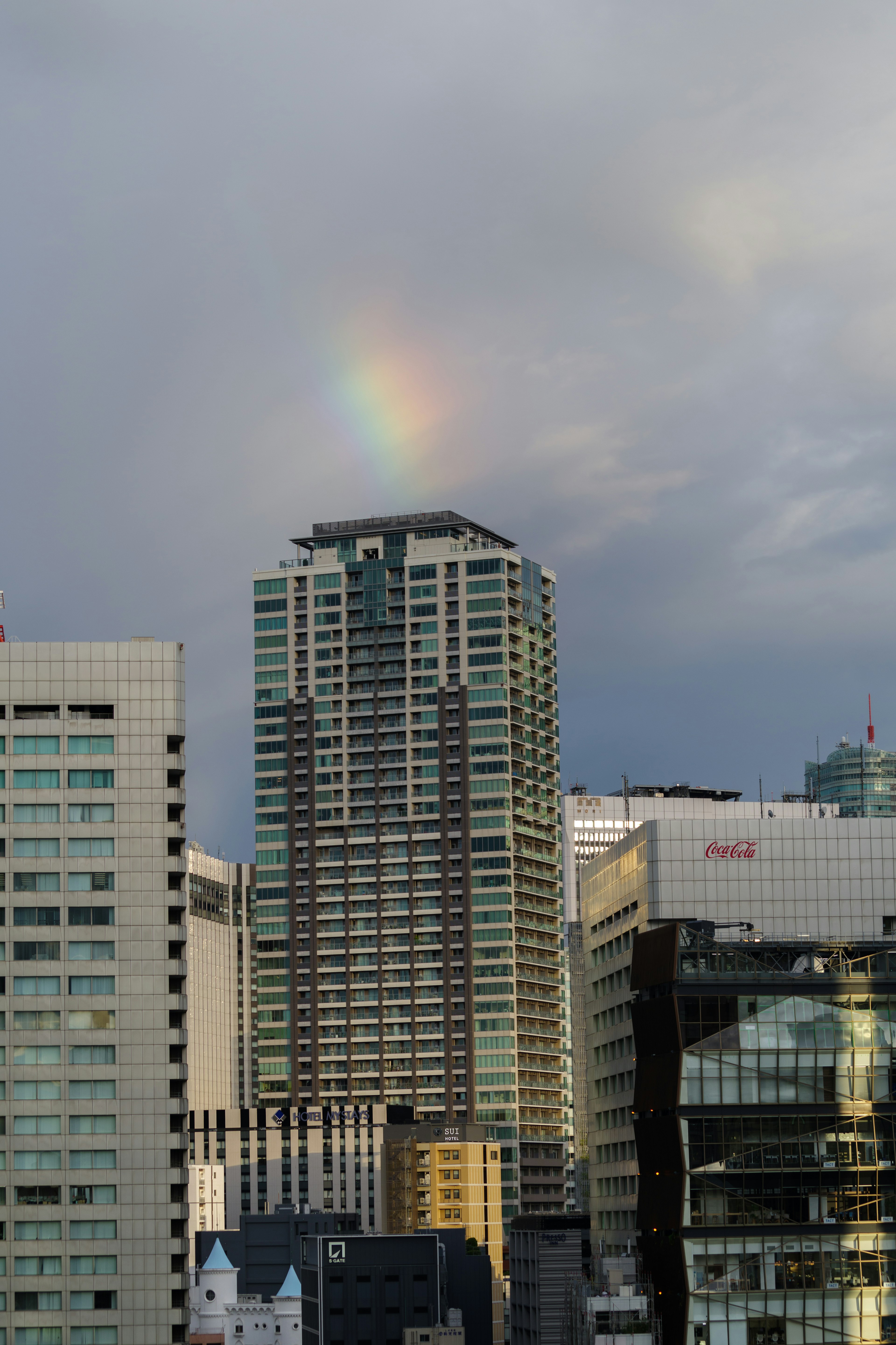 Rainbow over a skyscraper with cloudy sky