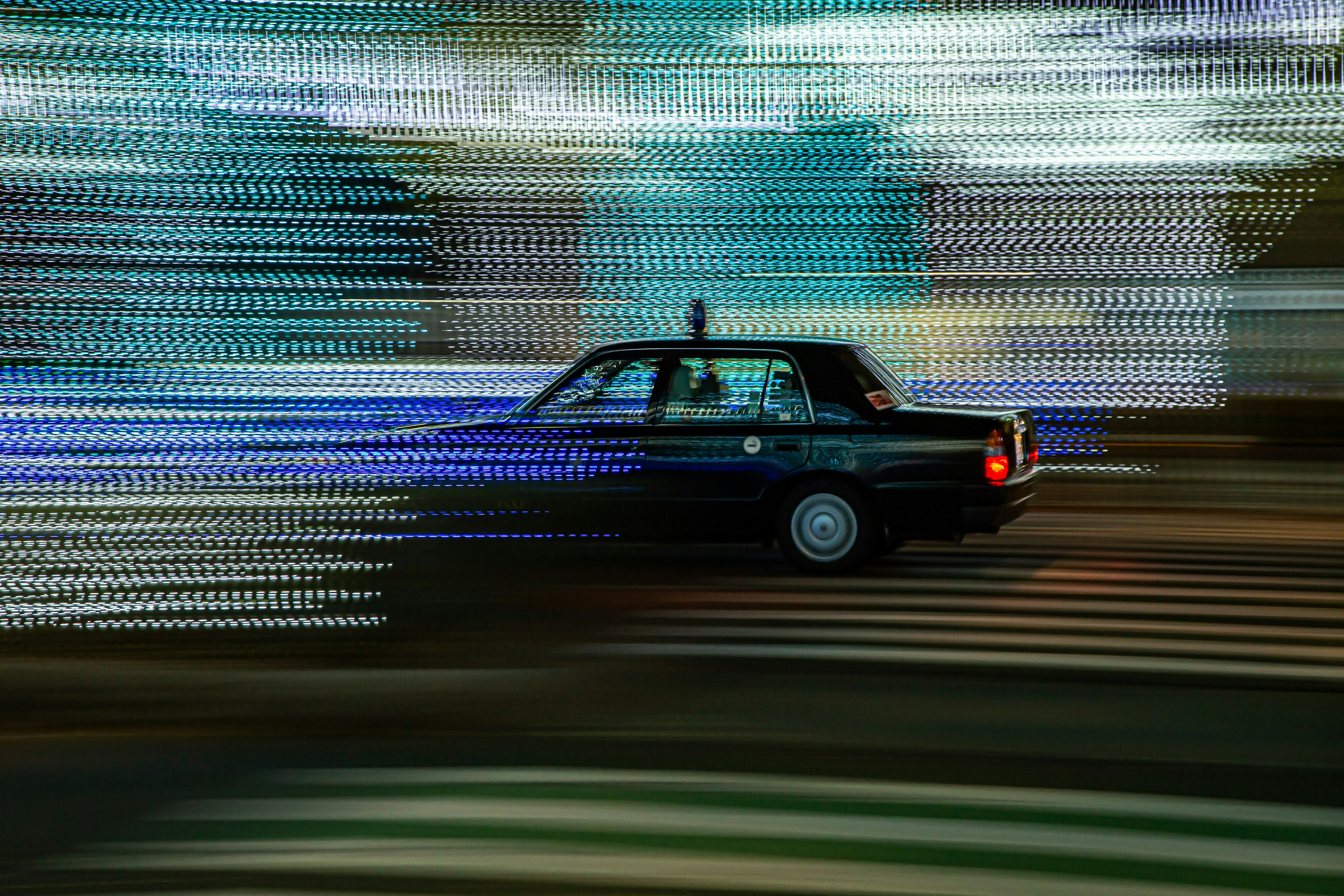 A black taxi speeding through vibrant light trails