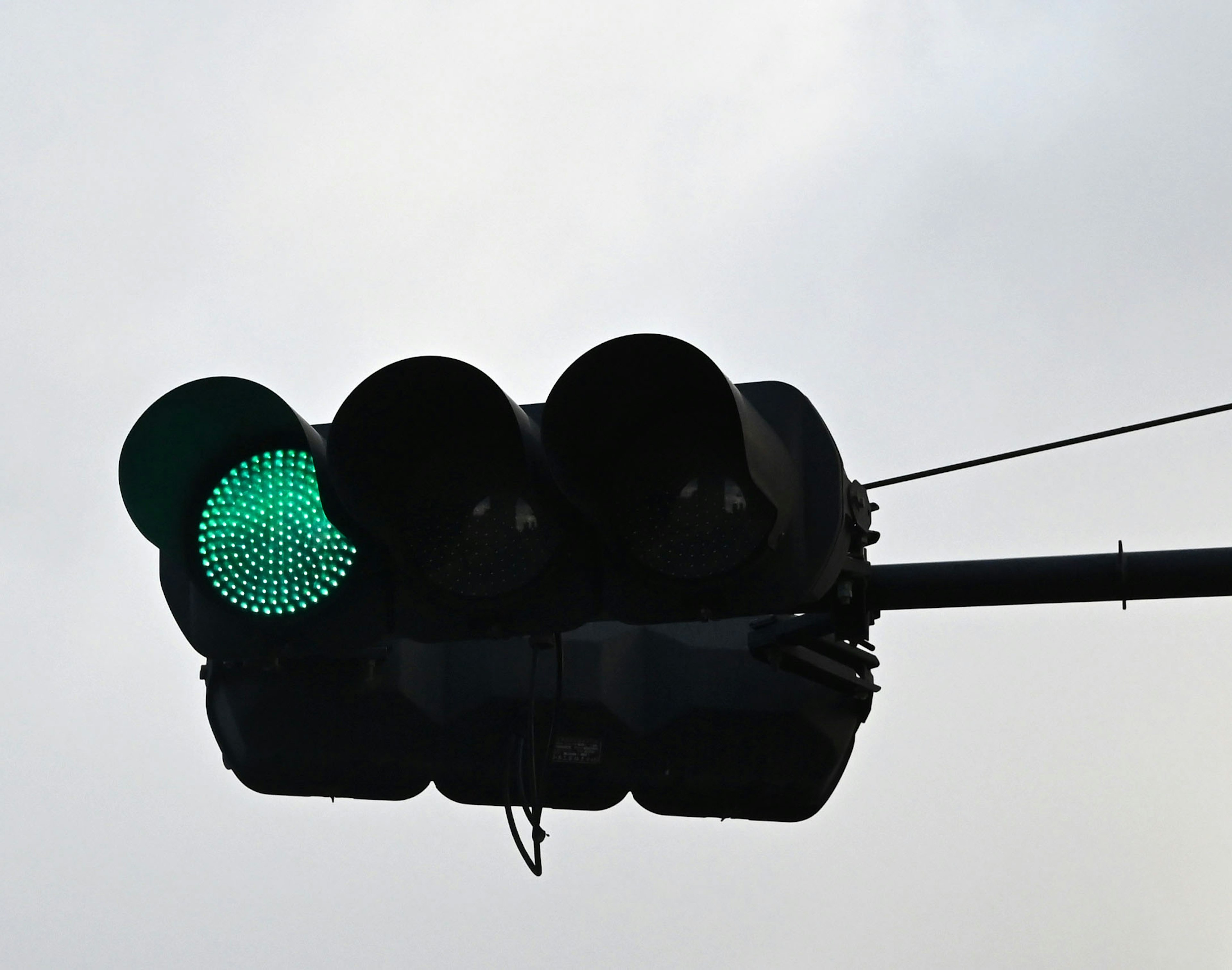 Green traffic light illuminated against a cloudy sky