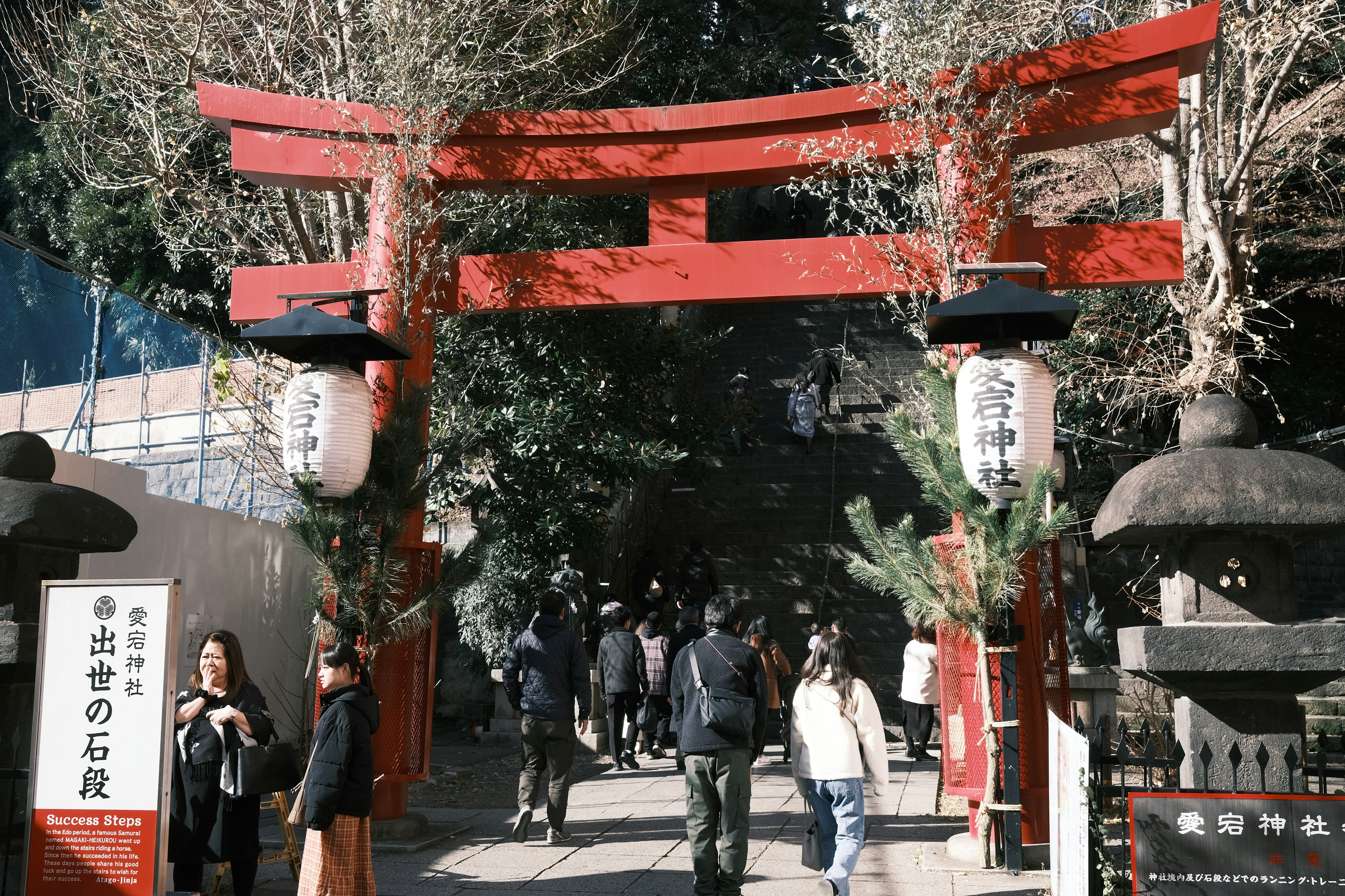 Entrada de un santuario con una puerta torii roja y visitantes