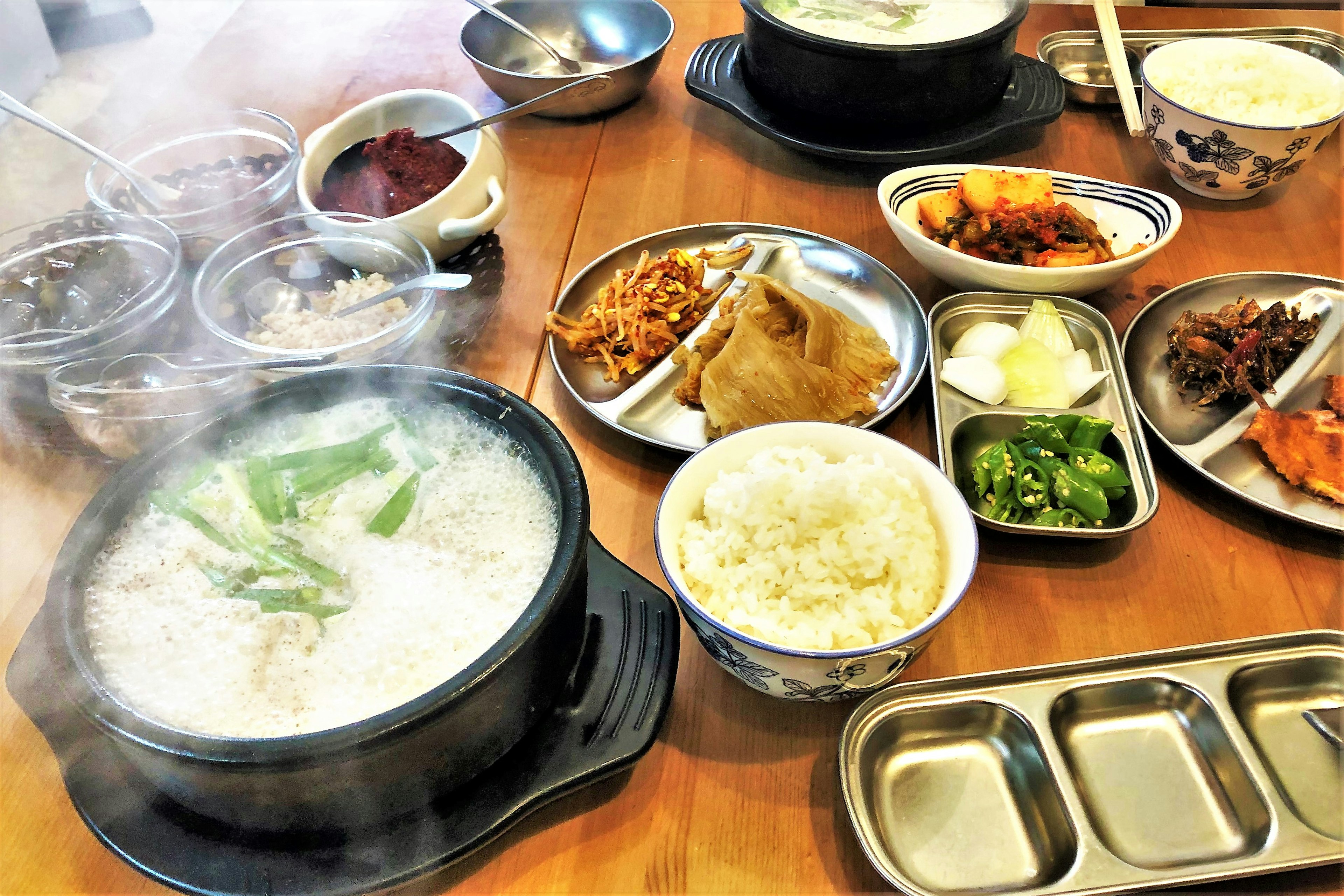 Steaming hot pot dish with various side dishes of Korean cuisine on a table