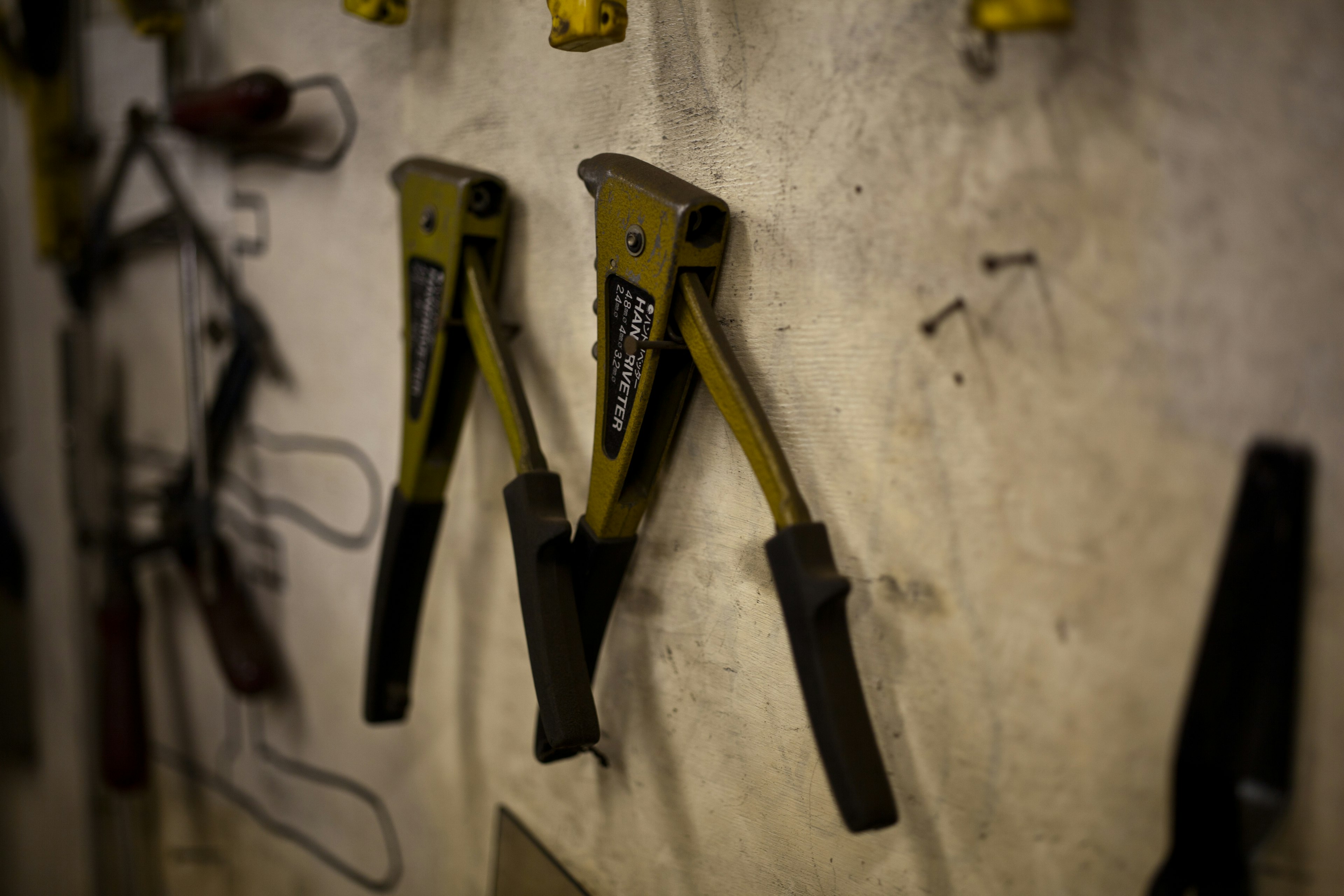 Yellow clamp tools with black handles mounted on a wall