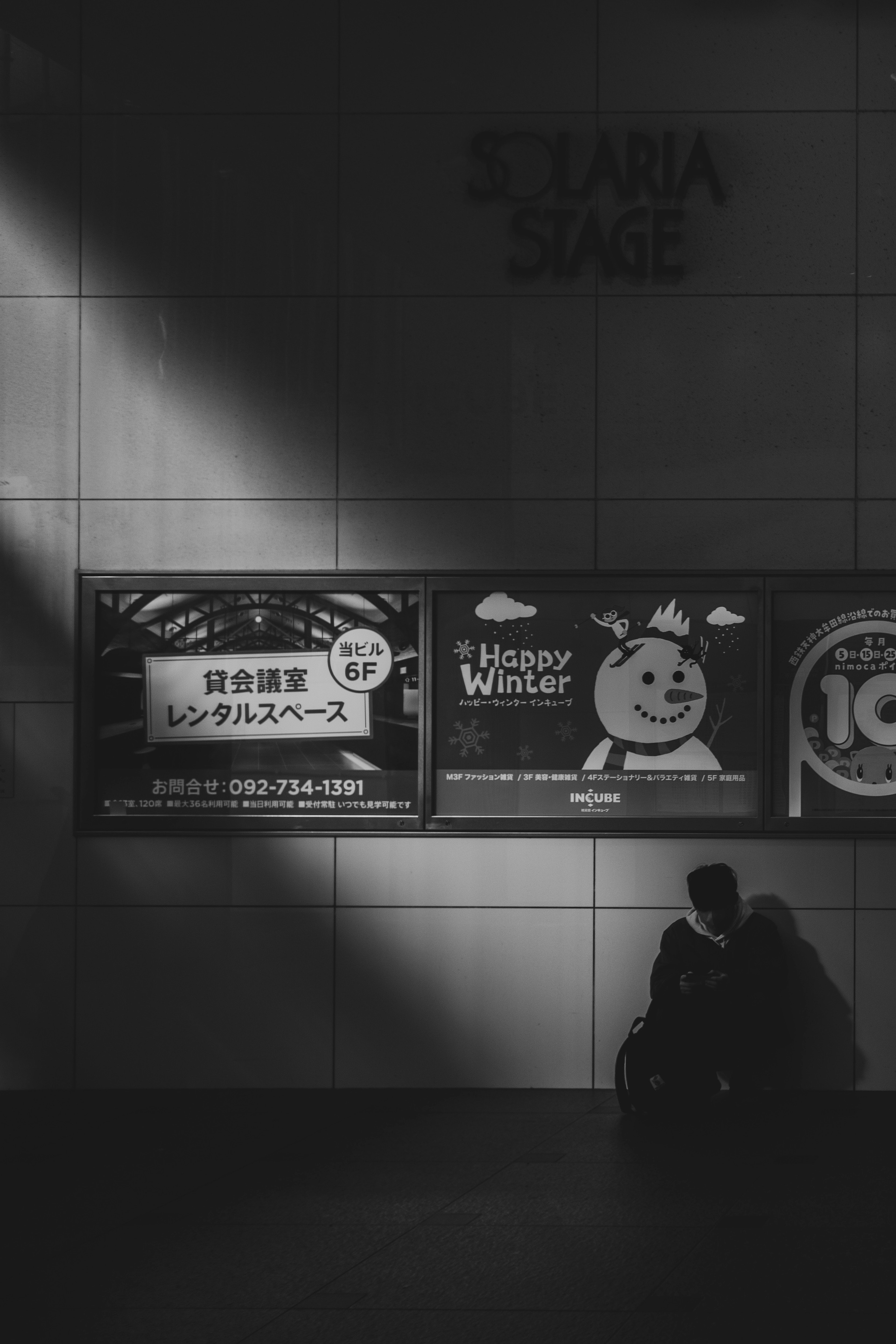 Couple assis dans l'ombre contre un mur avec des publicités