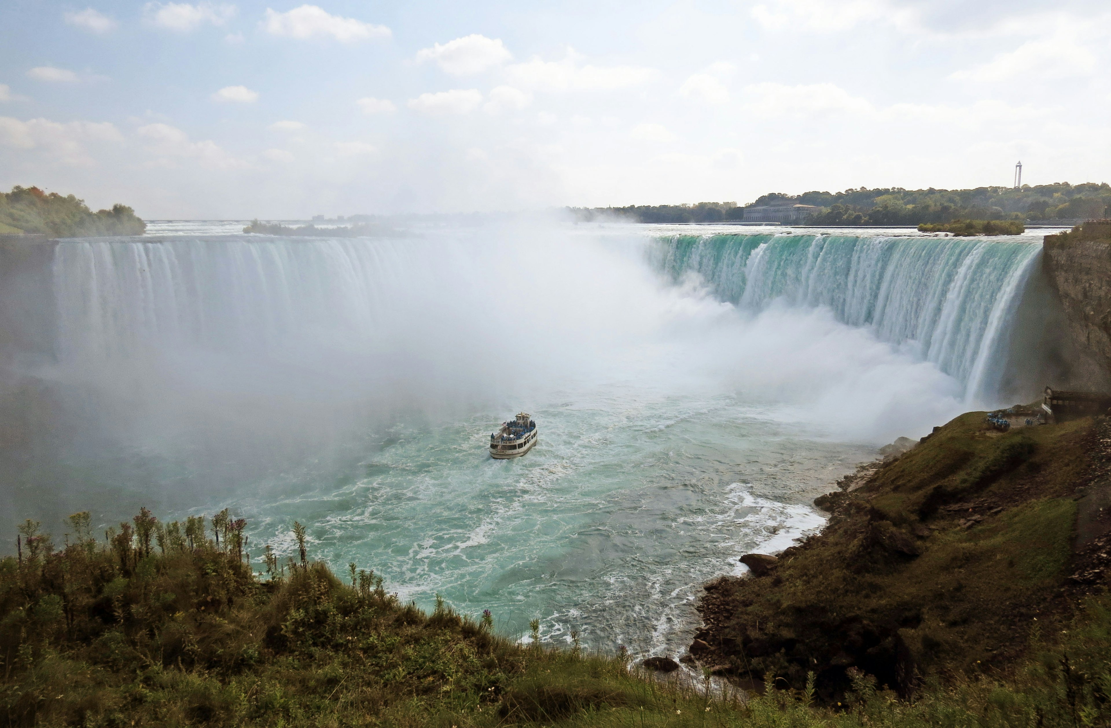 Vista majestuosa de las cataratas del Niágara con niebla que se eleva Cielo azul y nubes en contraste