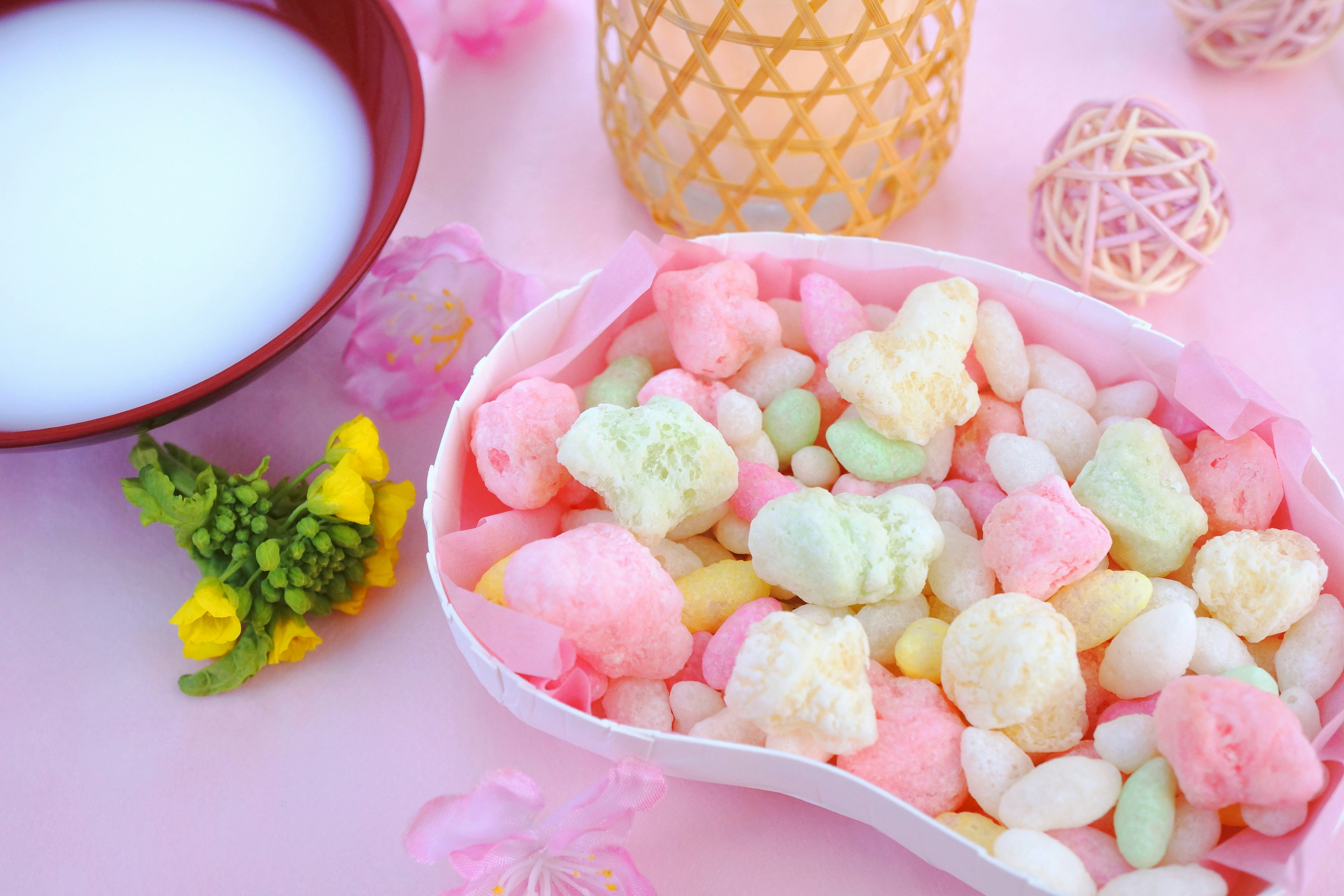 Colorful sweets display with a bowl of drink pink background with assorted pastel sweets