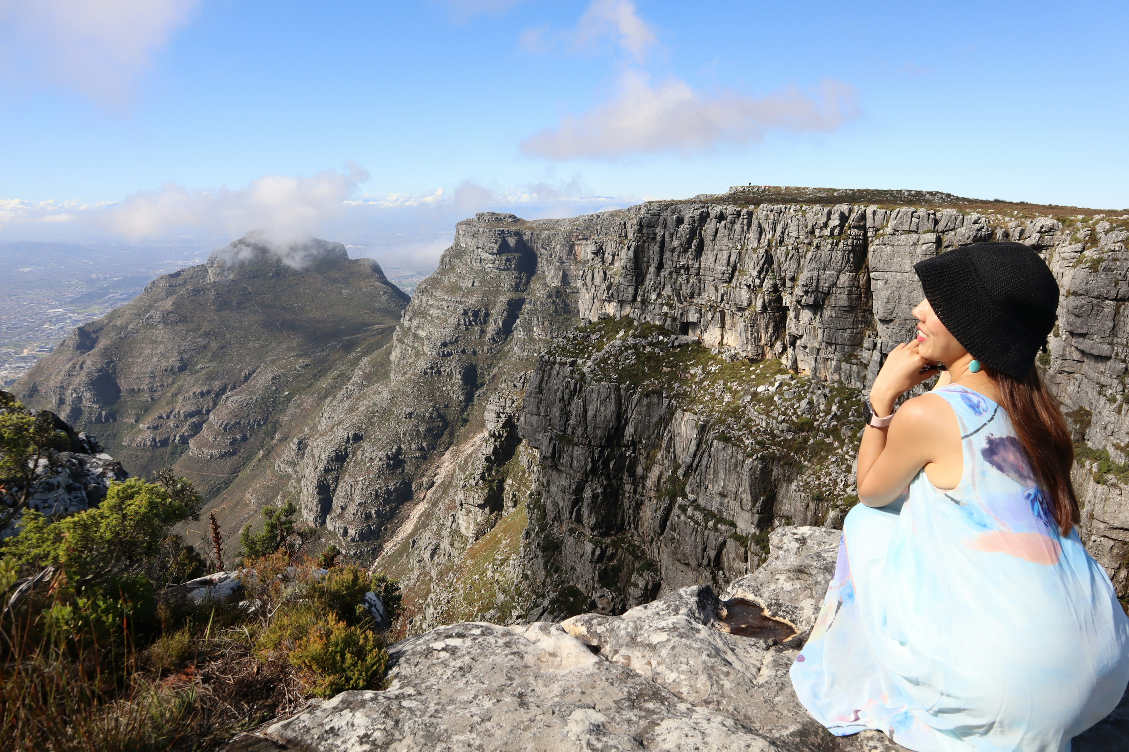 Femme assise sur une roche admirant une vue montagneuse époustouflante