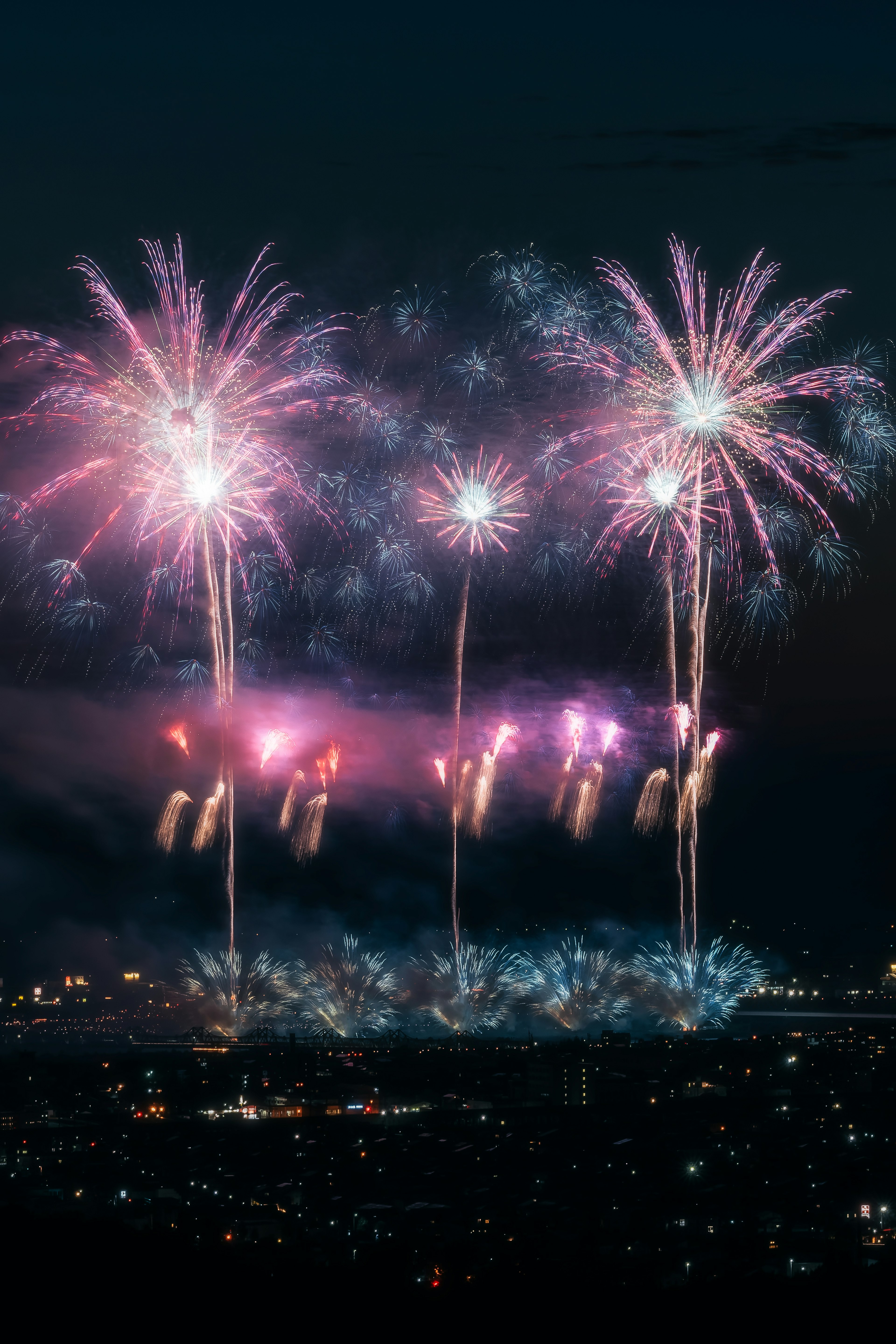 Fuegos artificiales coloridos estallan en el cielo nocturno sobre un paisaje urbano