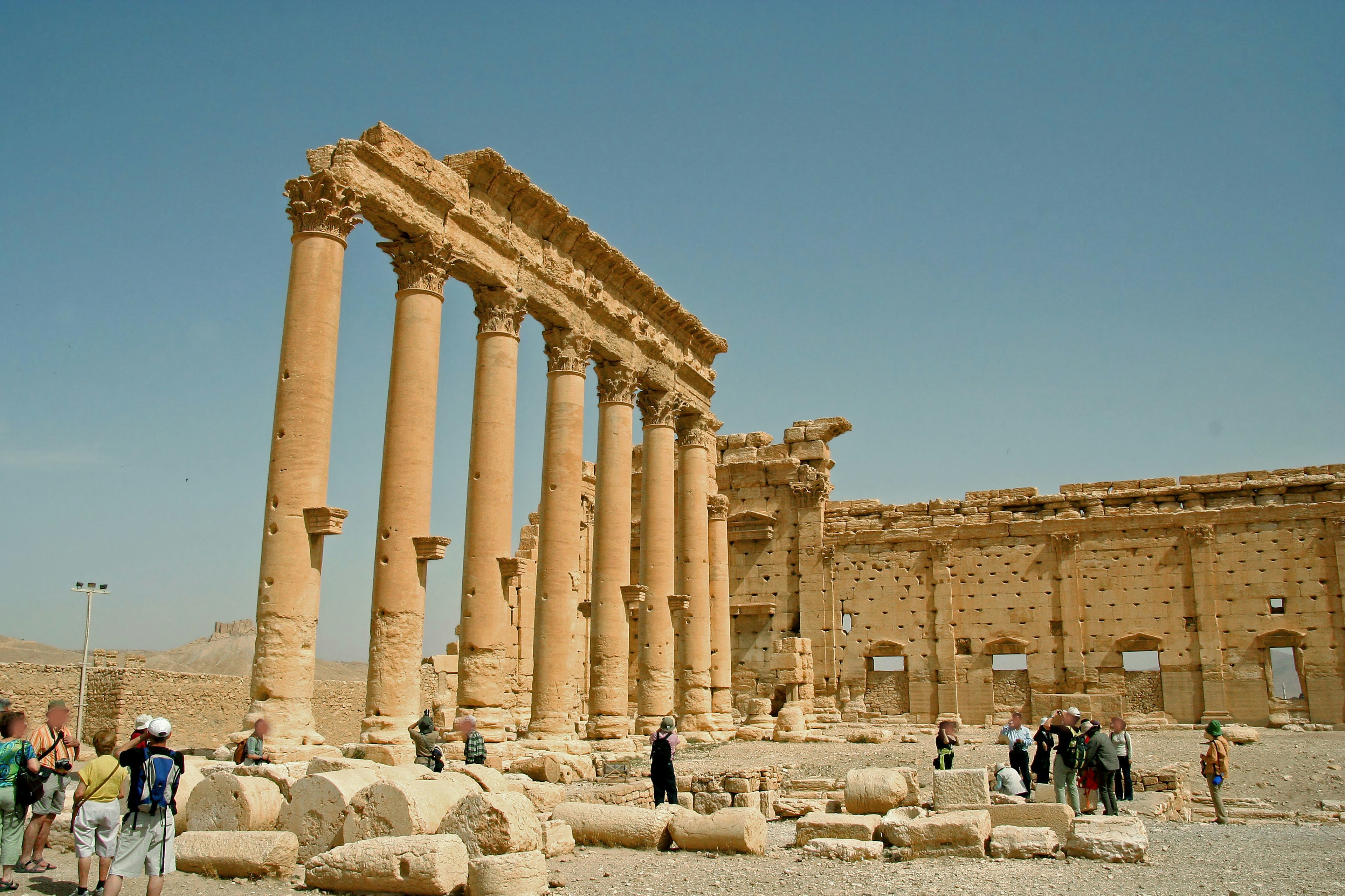 Ruinas antiguas con columnas en pie y un grupo de turistas