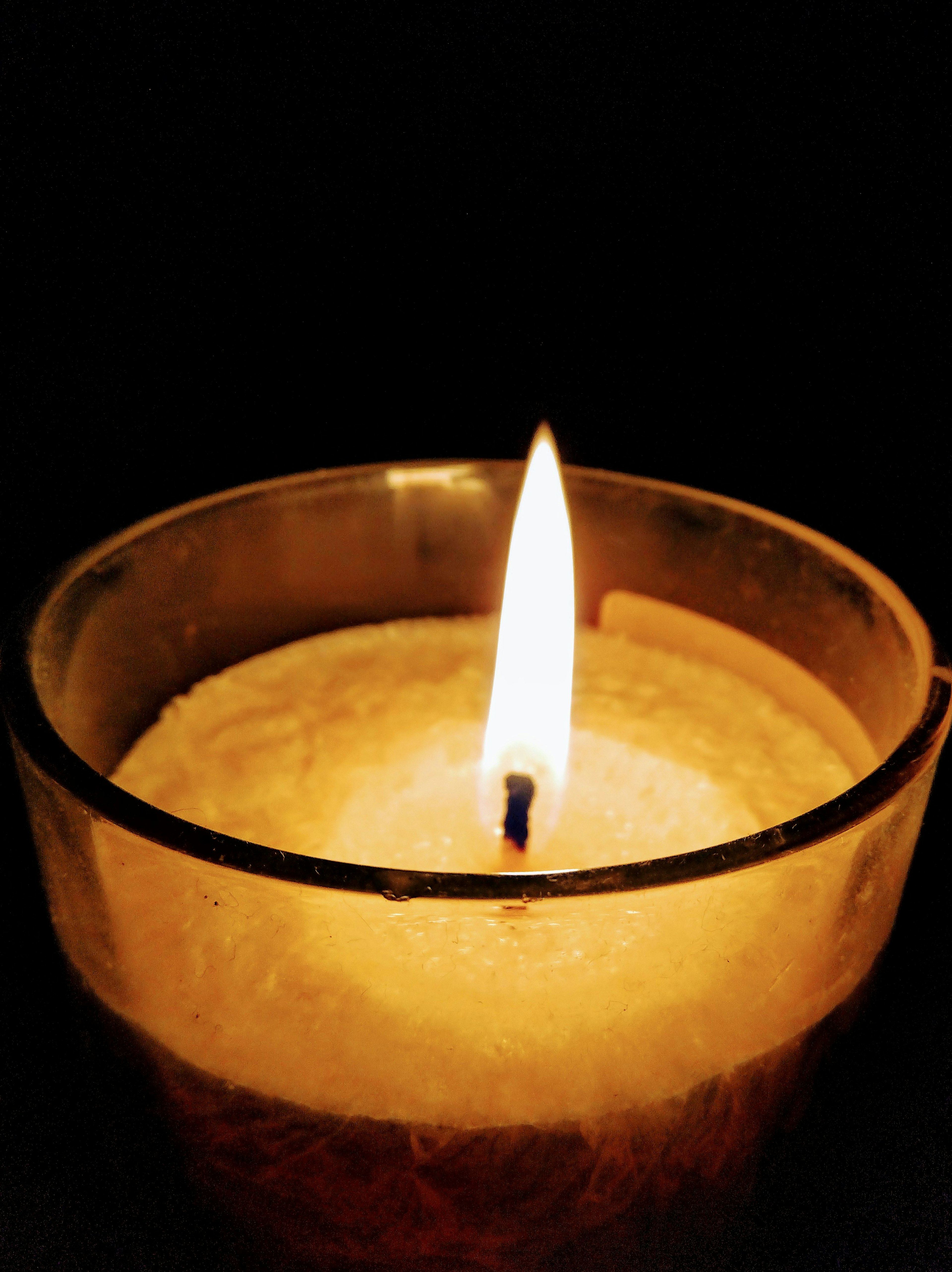 A candle flame glowing against a dark background