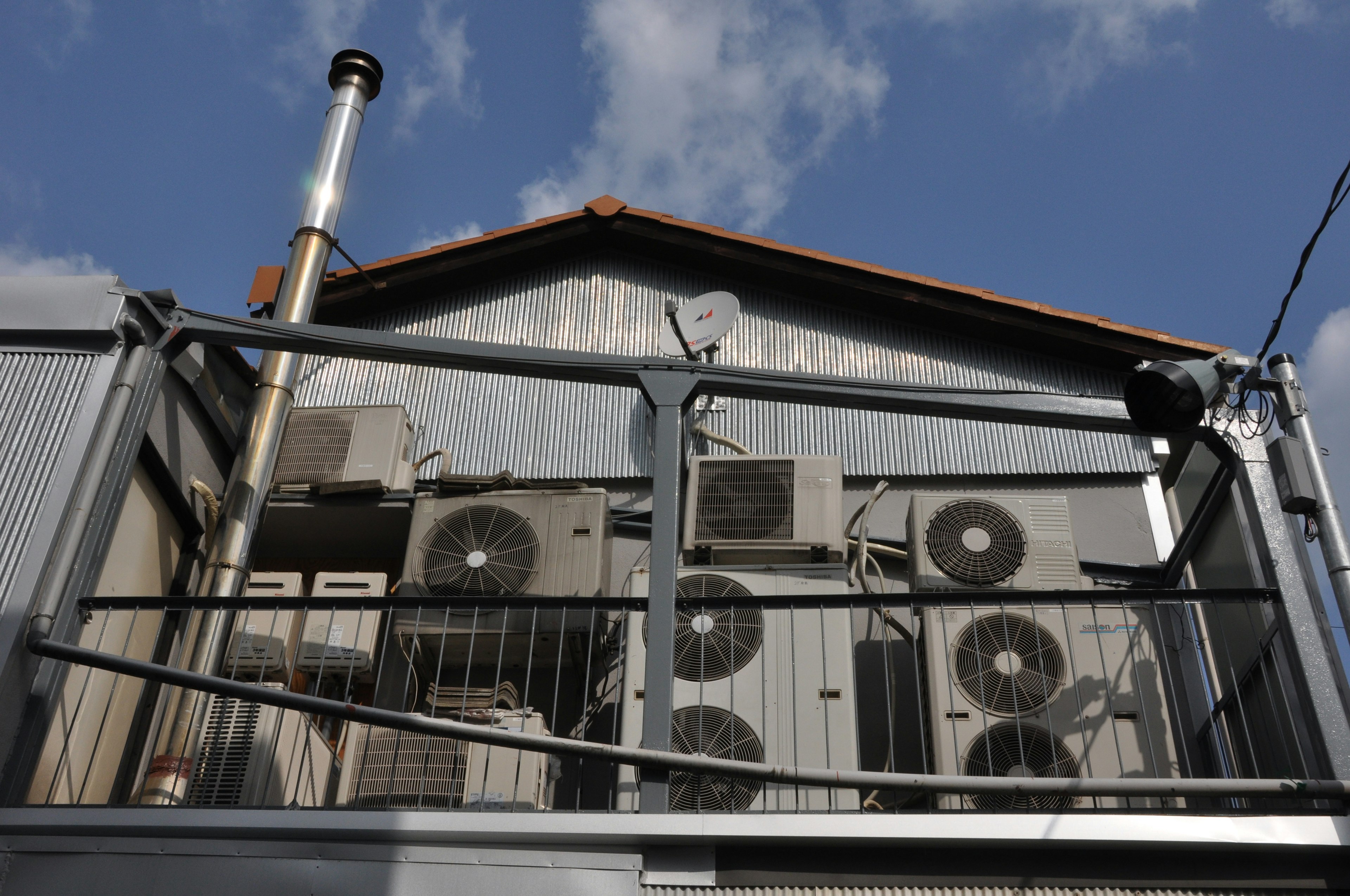 Industrial building with multiple air conditioning units and a chimney on the roof