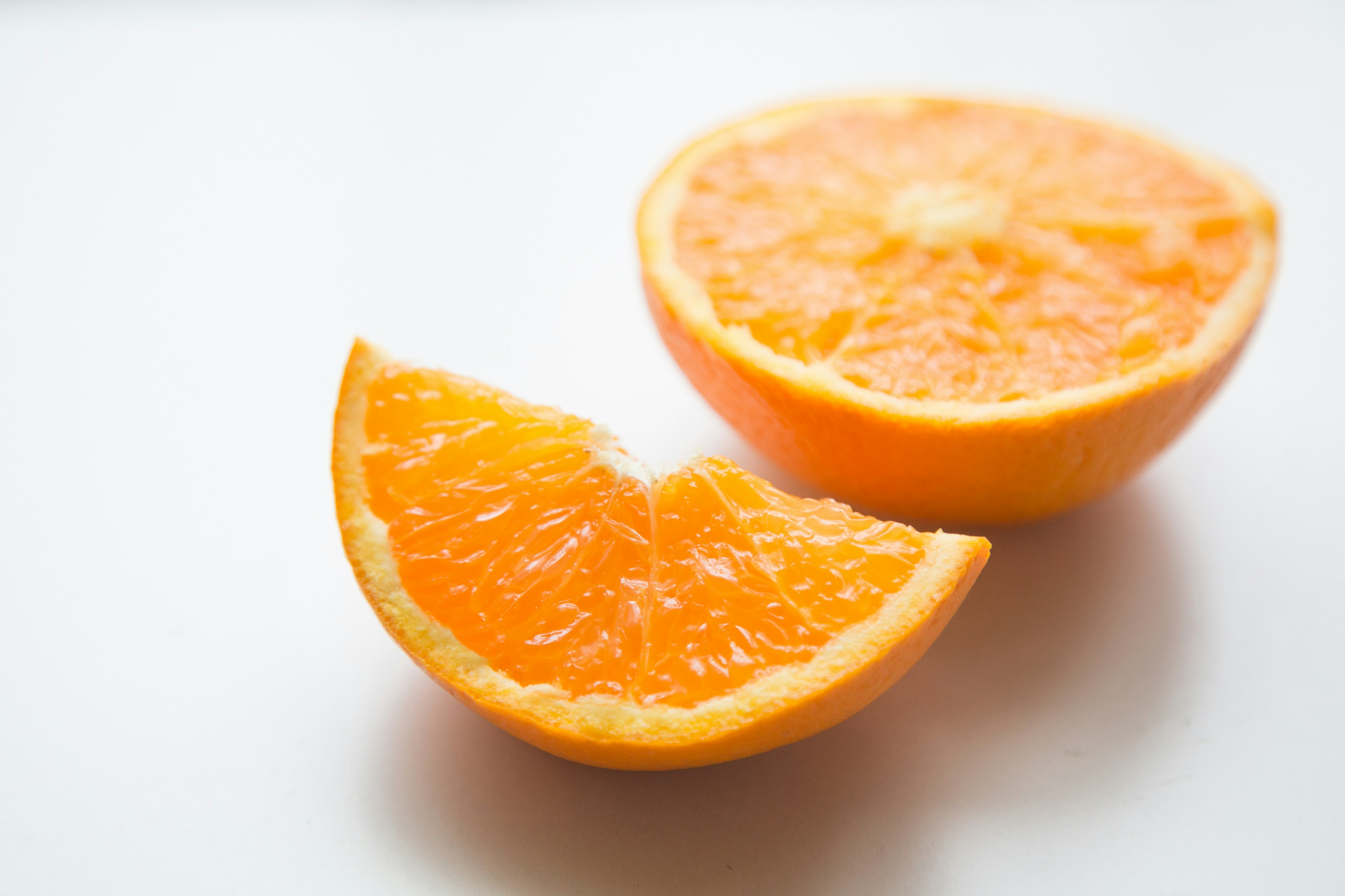 Una mitad de naranja vibrante y una cuña sobre un fondo blanco