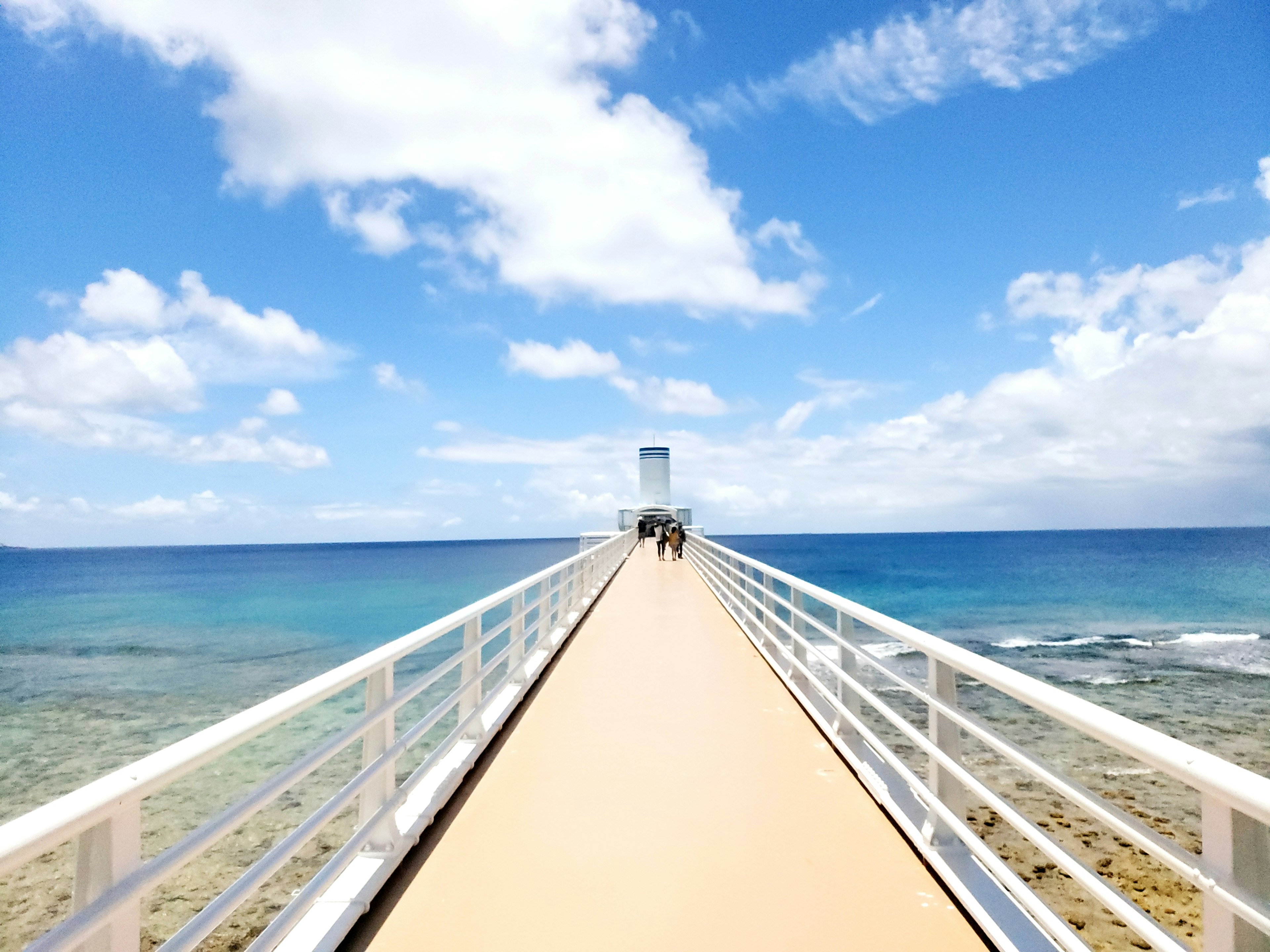 Vista escénica de un muelle que se extiende sobre aguas oceánicas azules