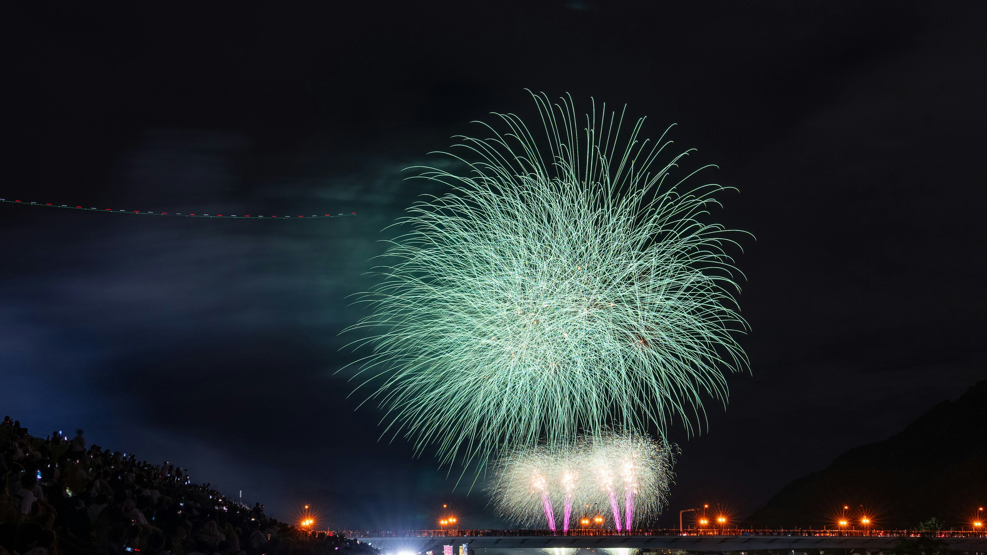 夜空に輝く緑色の花火が打ち上げられている光景