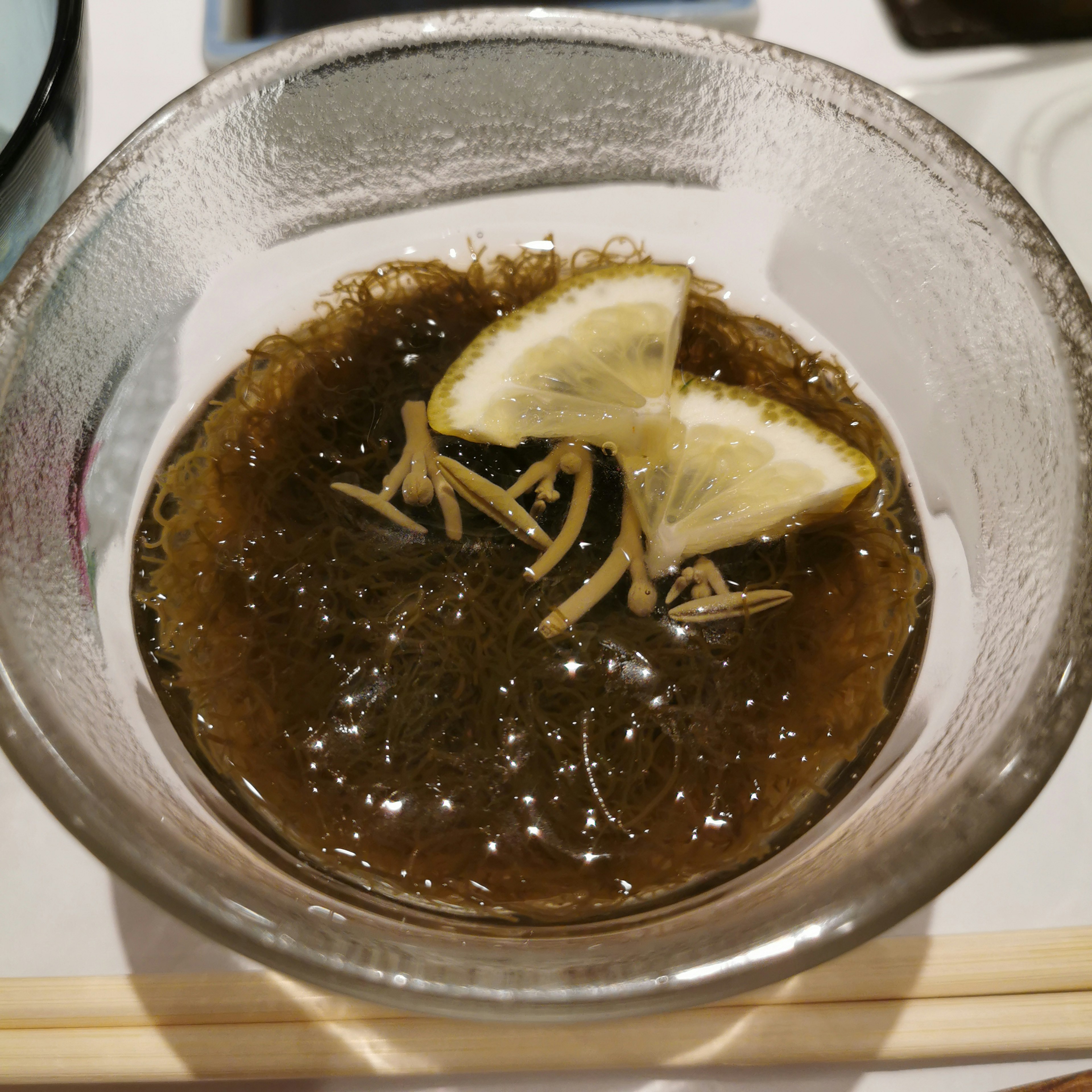 Seaweed salad served in a clear bowl topped with lemon slices and ginger