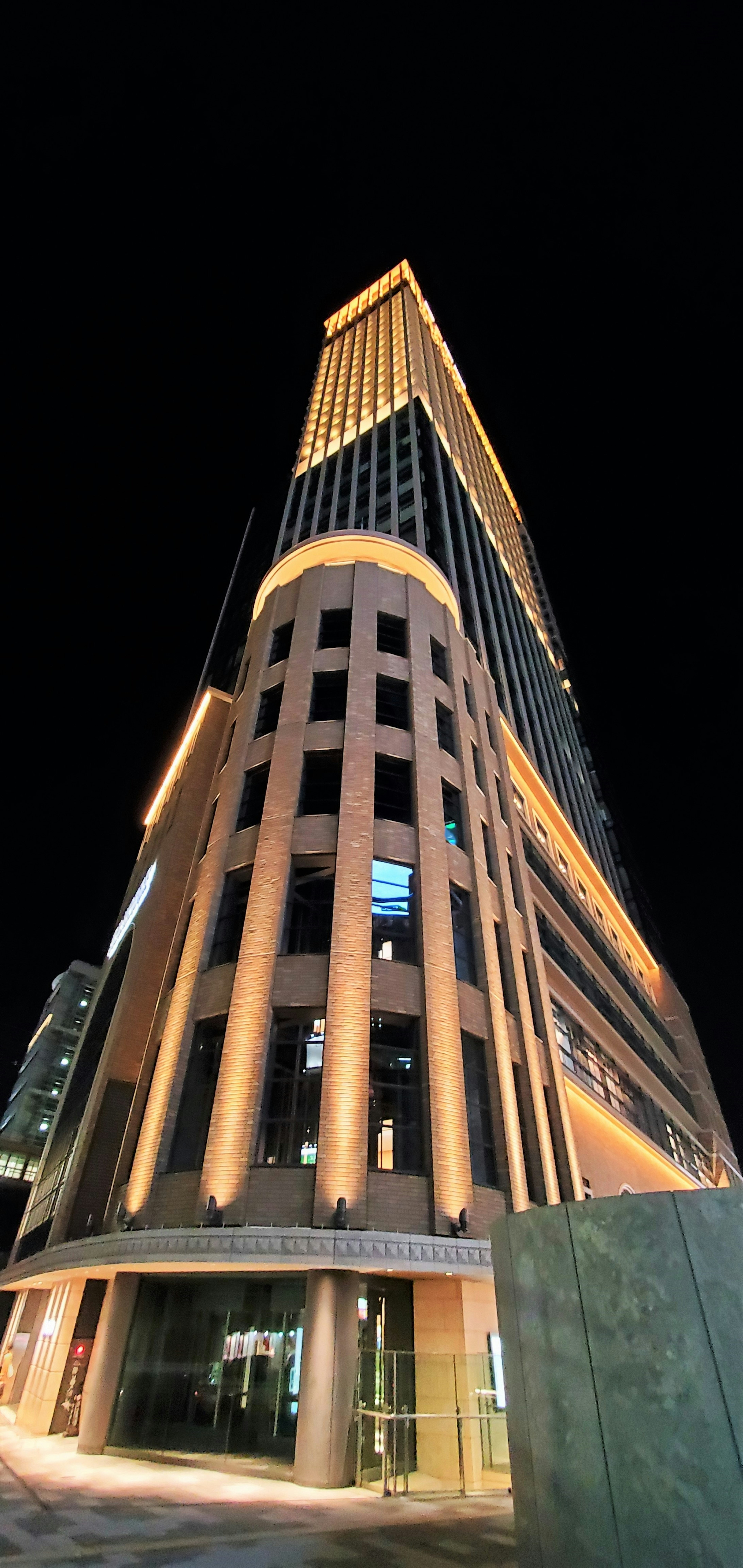 Alto rascacielos de noche con diseño arquitectónico único resaltado por una iluminación brillante