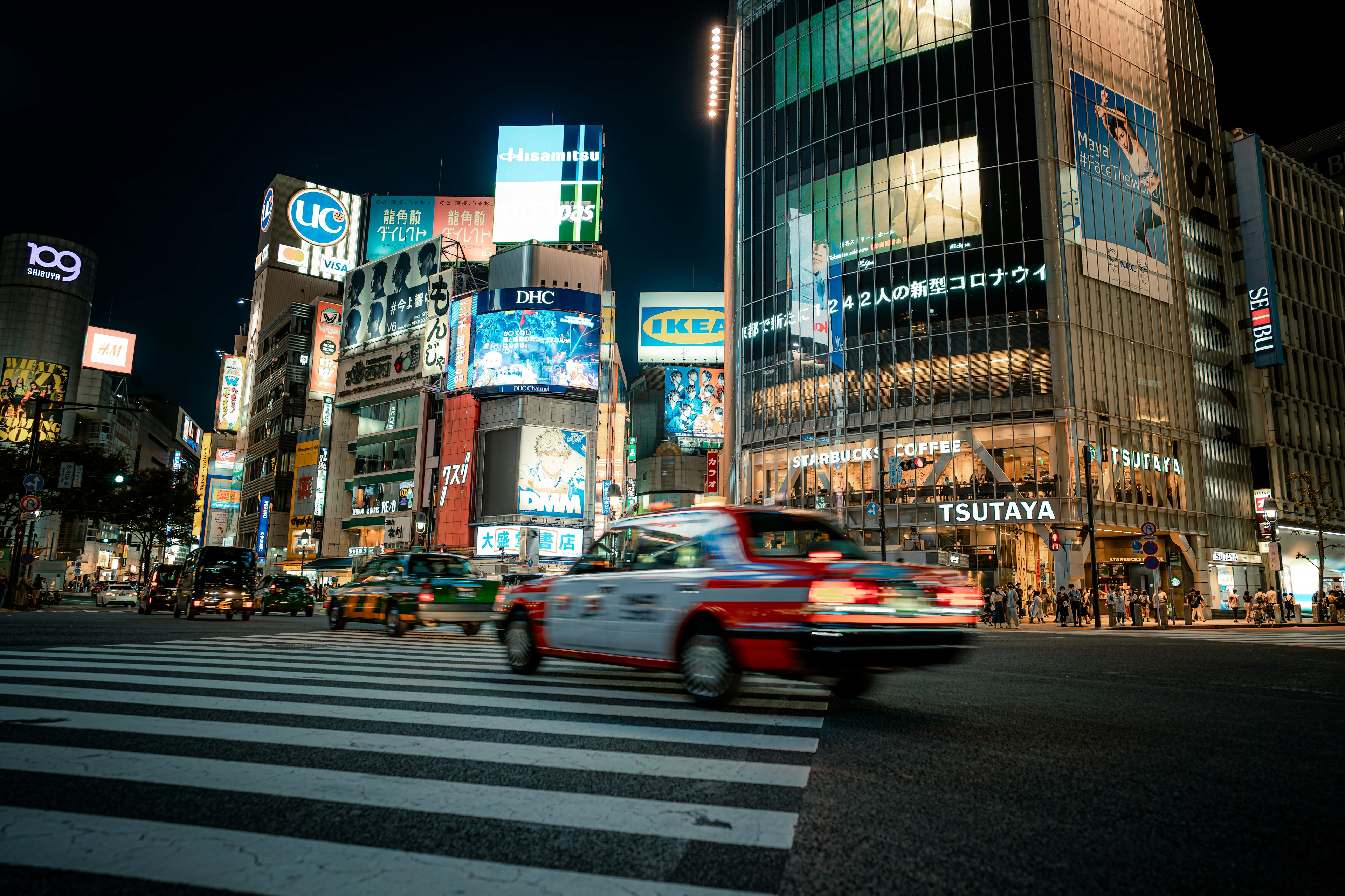 Nachtansicht von Shibuya Crossing Taxi überquert den Fußgängerüberweg helle Gebäudelichter