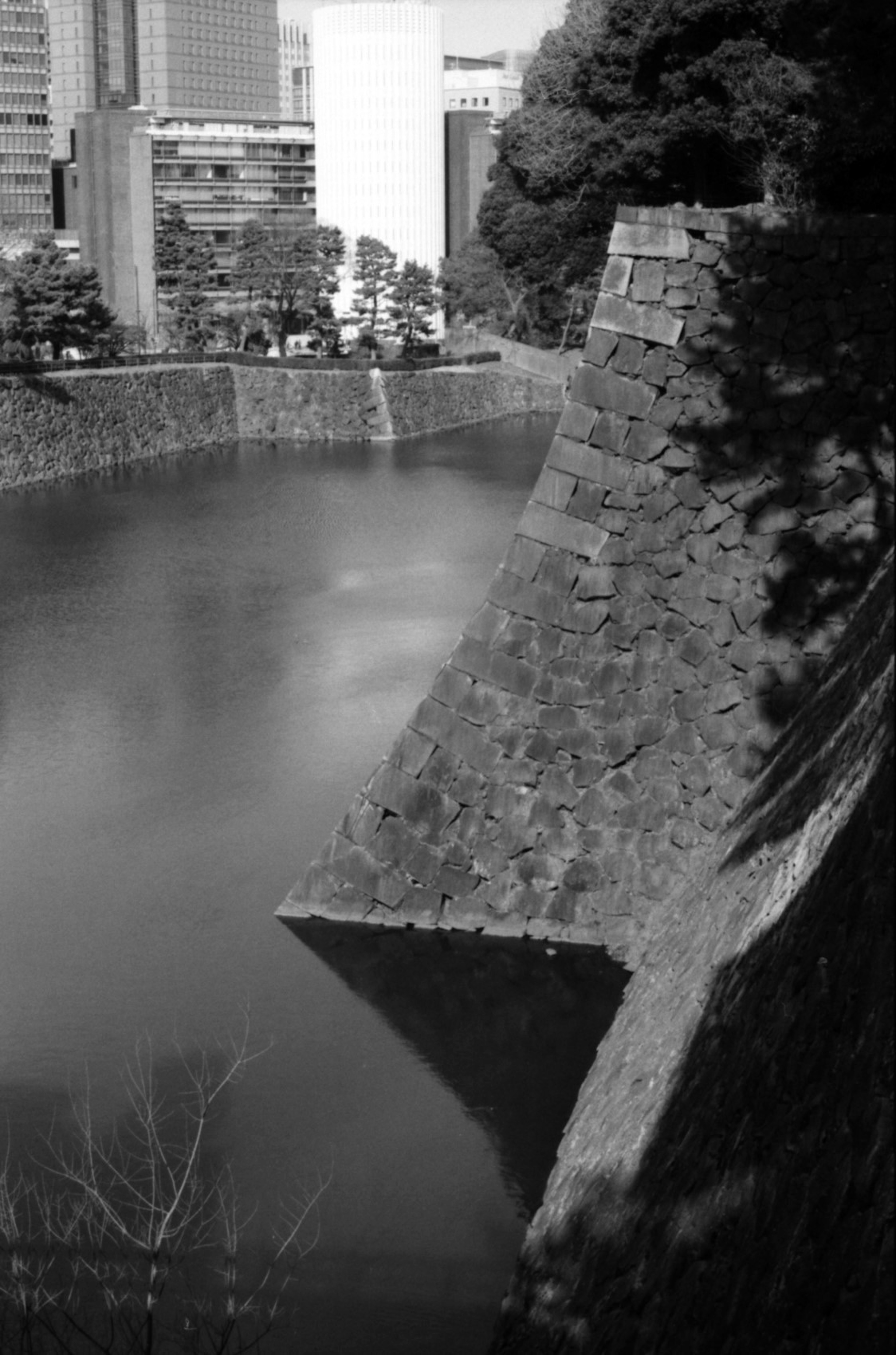 Imagen en blanco y negro de una muralla de castillo con una superficie de agua tranquila