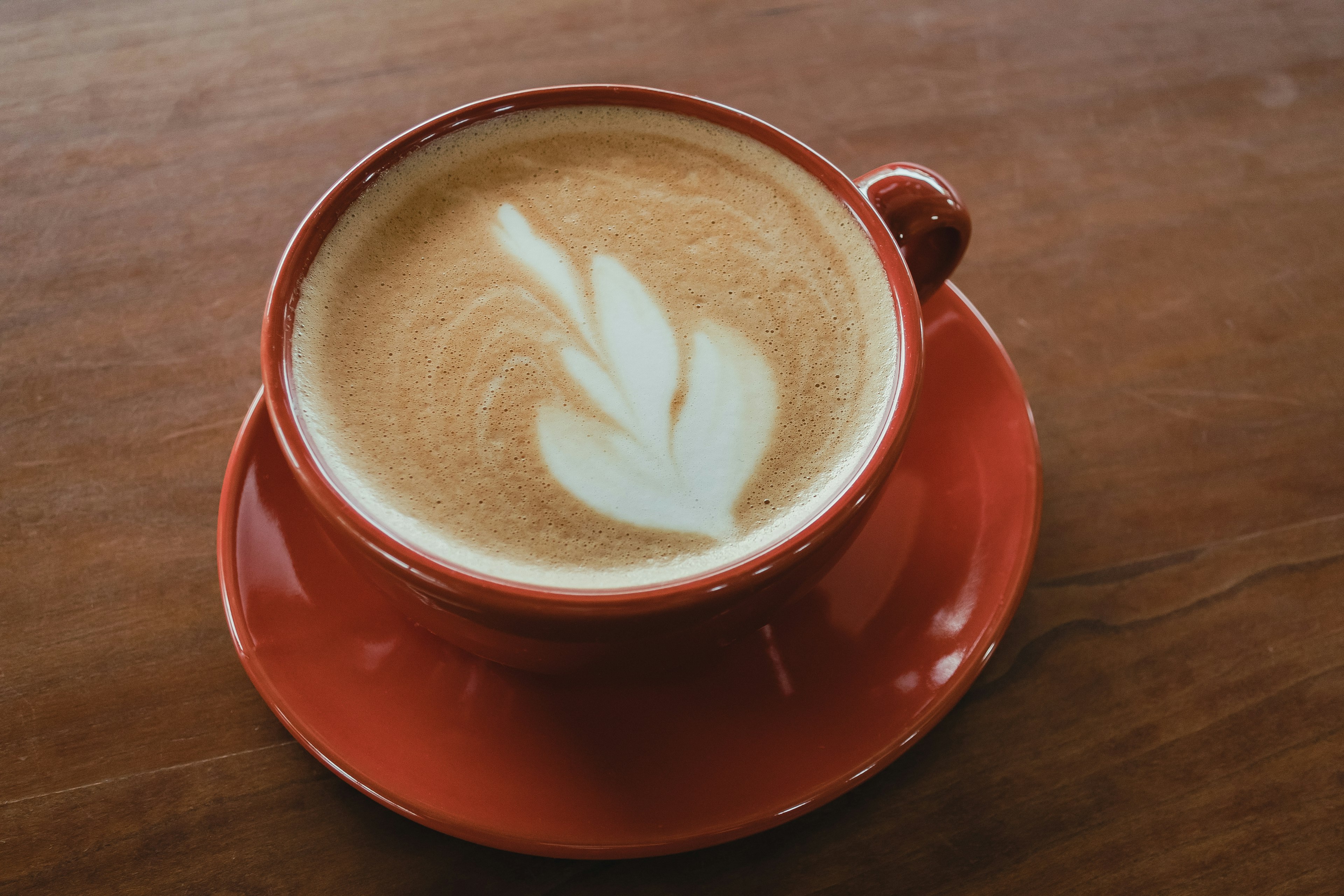 Kopi dengan seni latte dalam cangkir merah