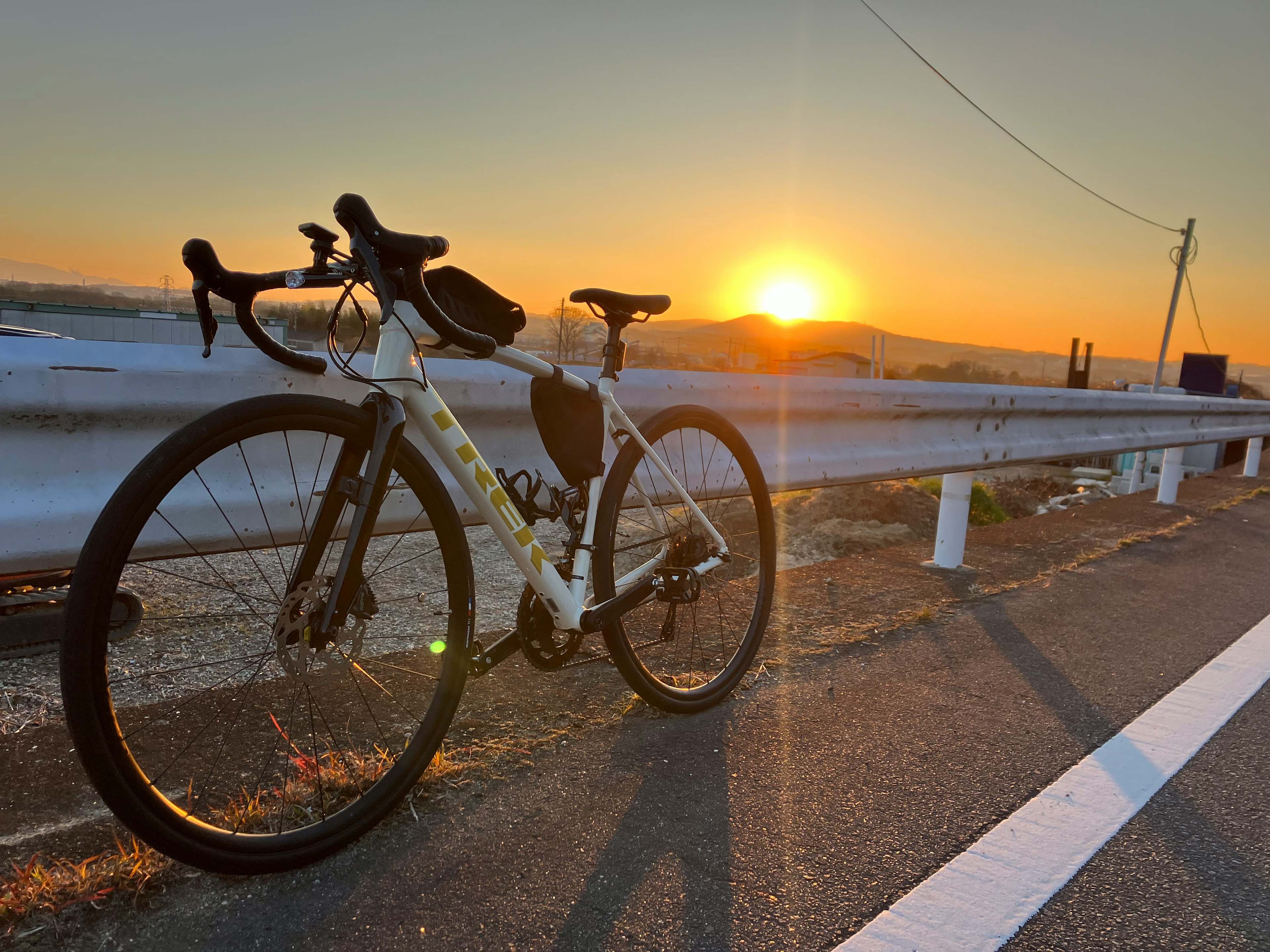 夕日を背景にした白い自転車と道路