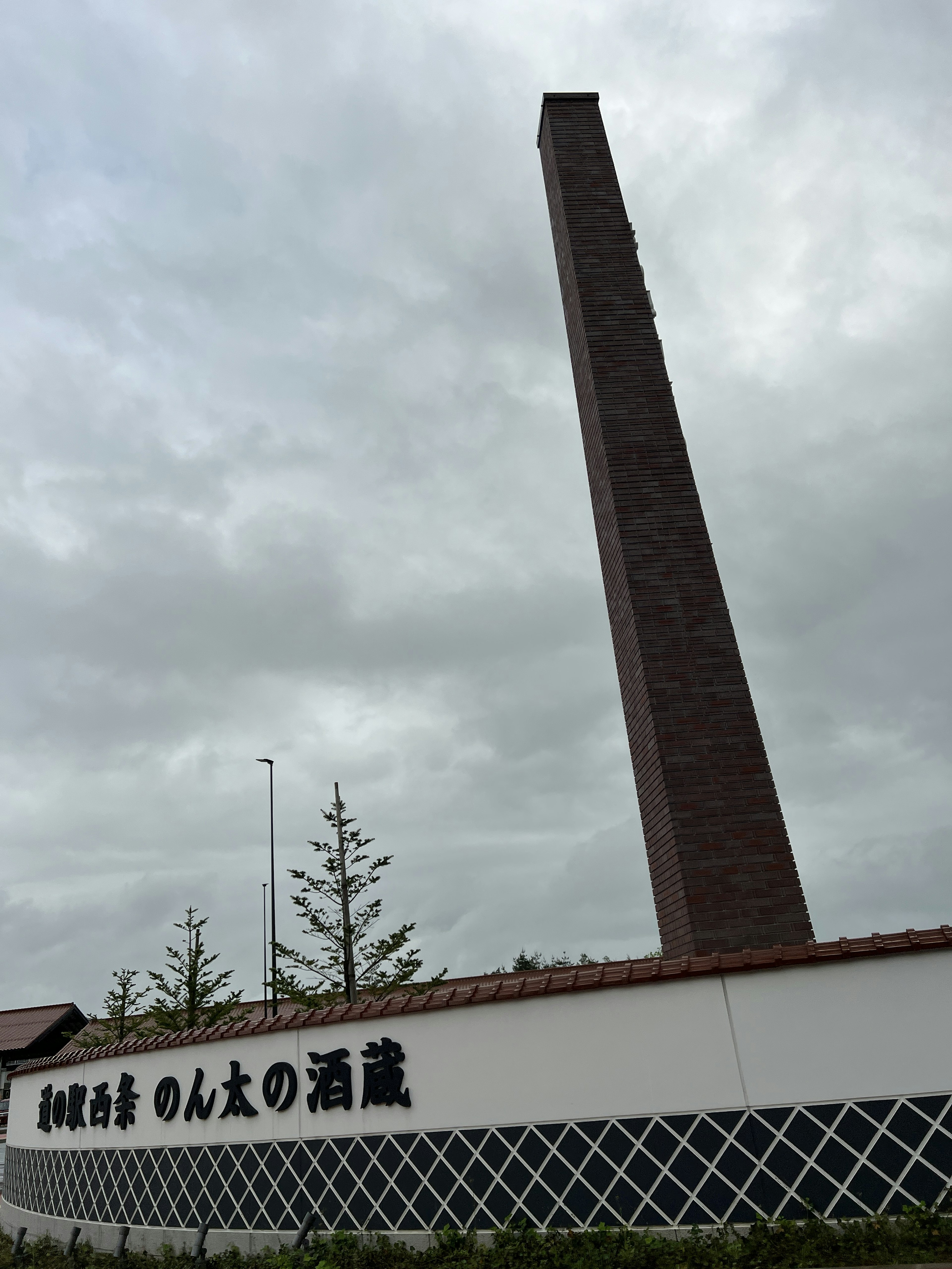 Exterior of a Japanese sake brewery featuring a tall brick chimney