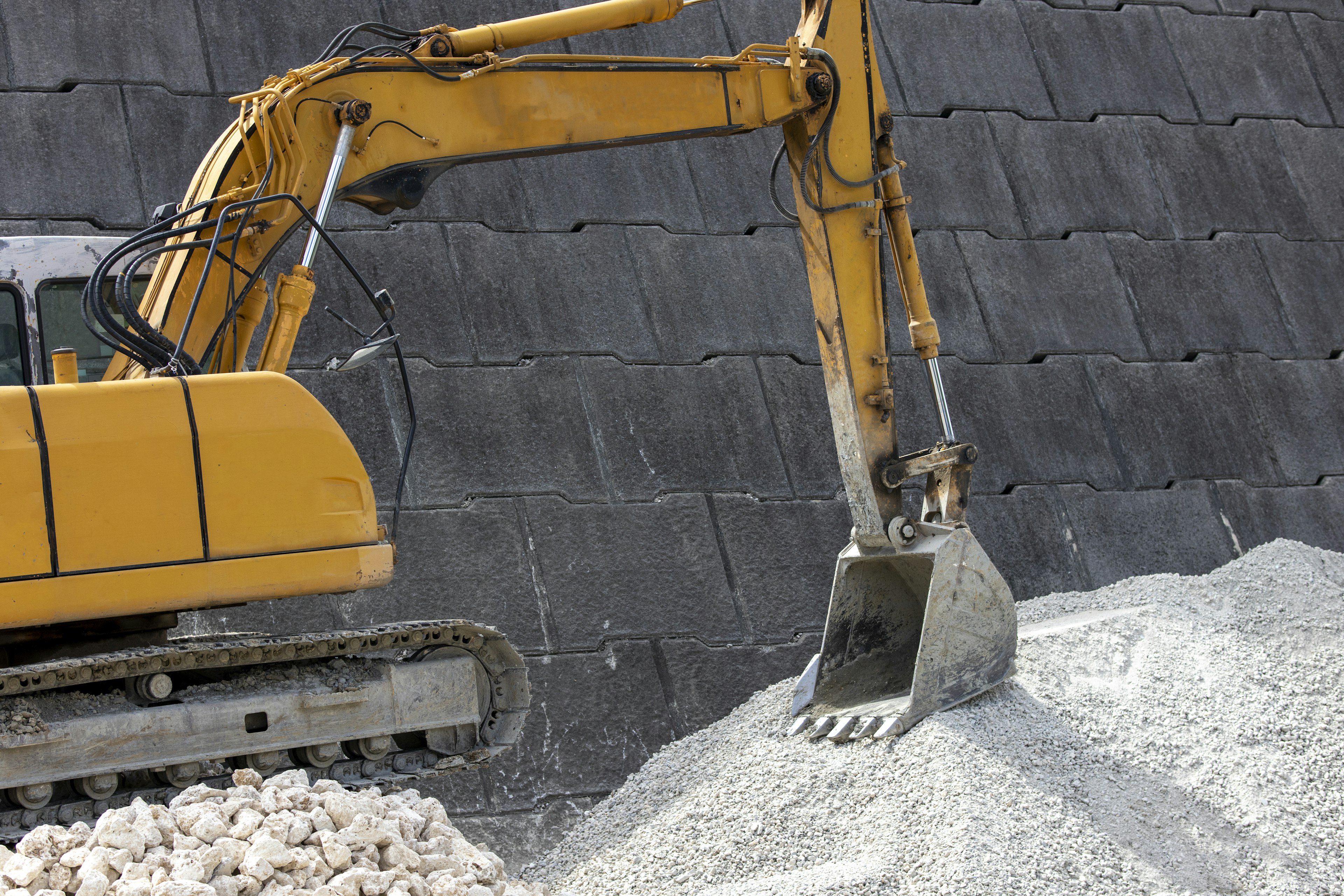 Excavatrice jaune travaillant sur un chantier avec un tas de gravier blanc