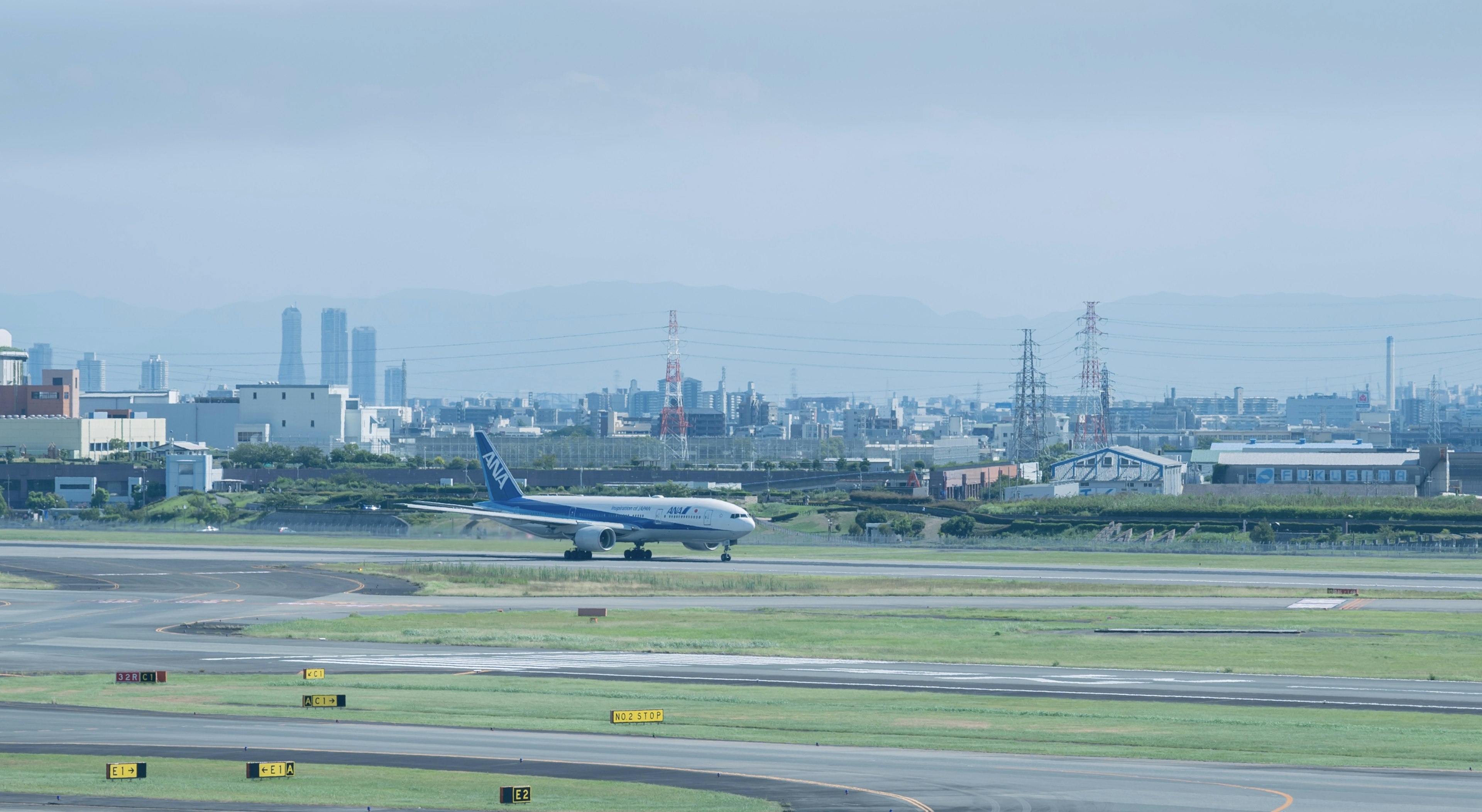 Airplane taxiing on runway with industrial background