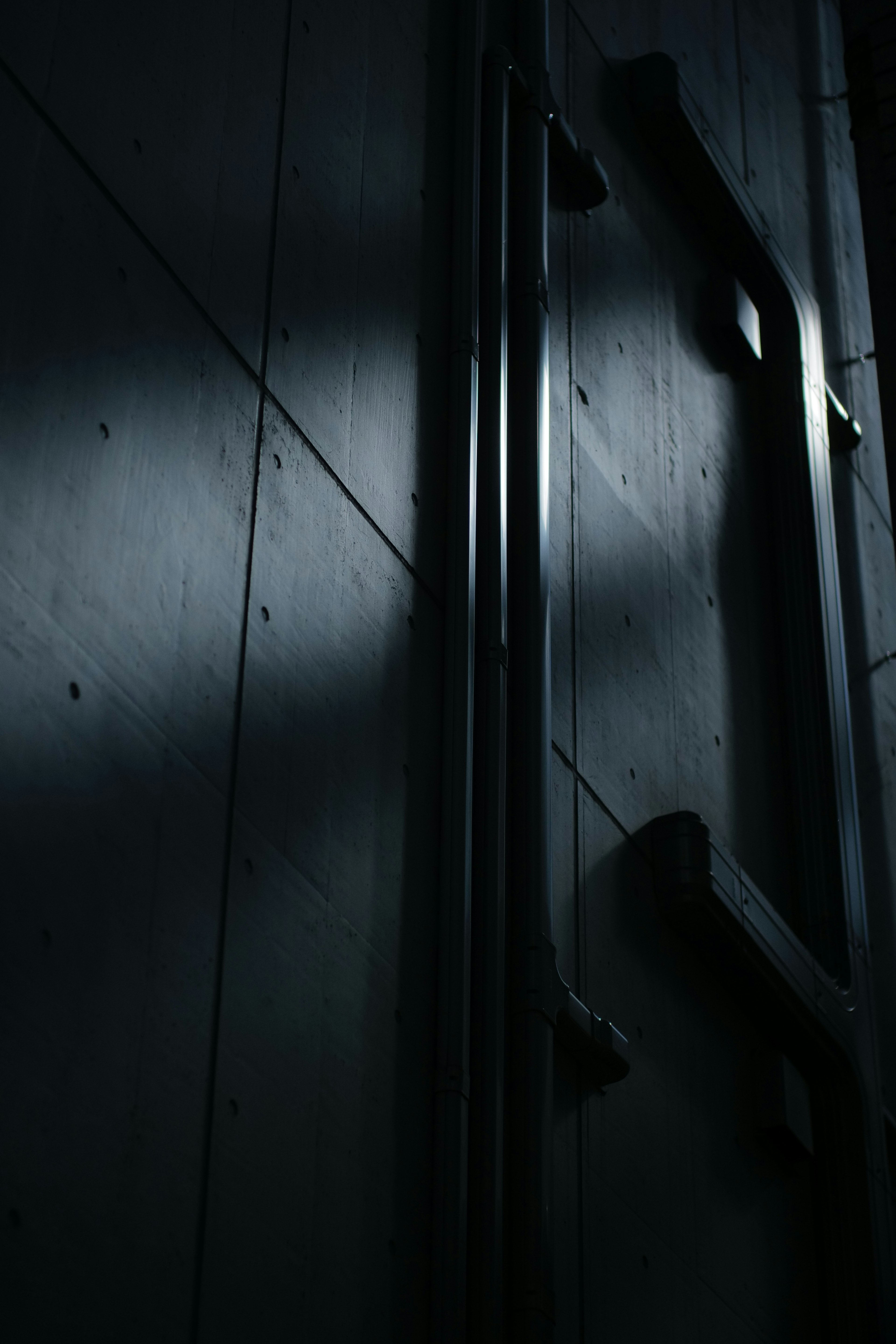 Part of a door with contrasting light and shadow on a black wall