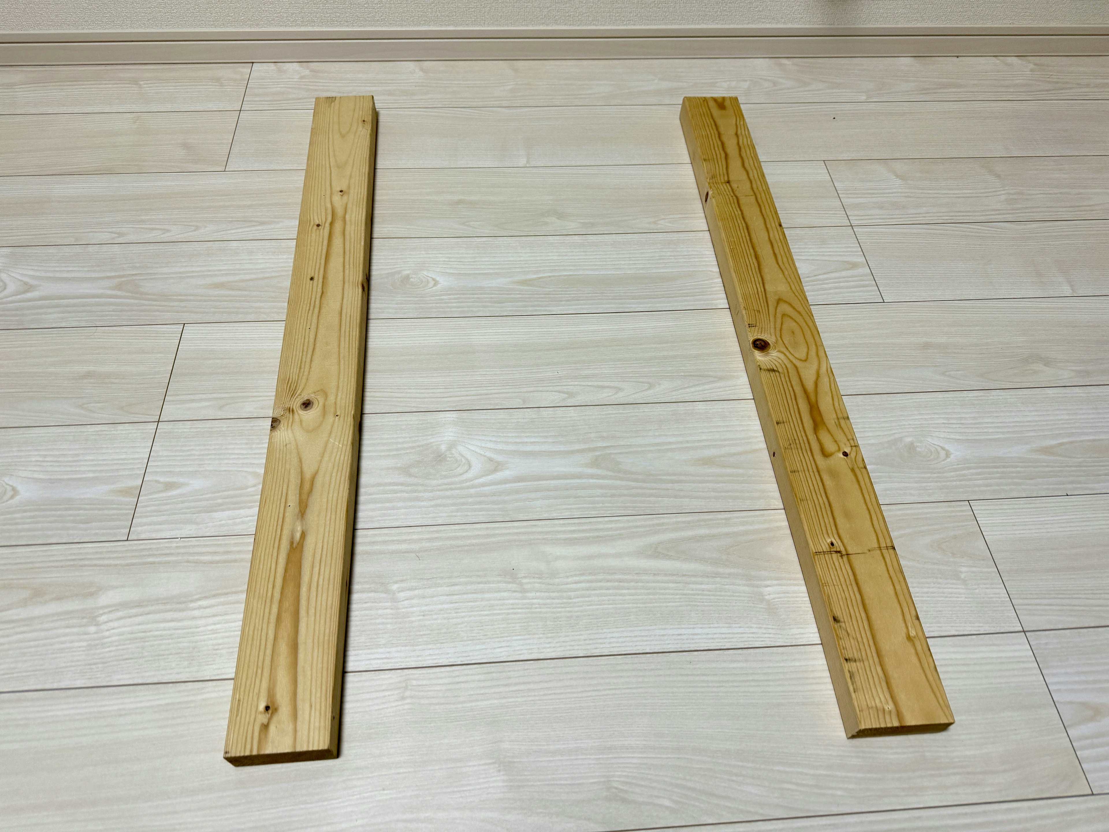 Two wooden planks placed parallel on a light-colored floor