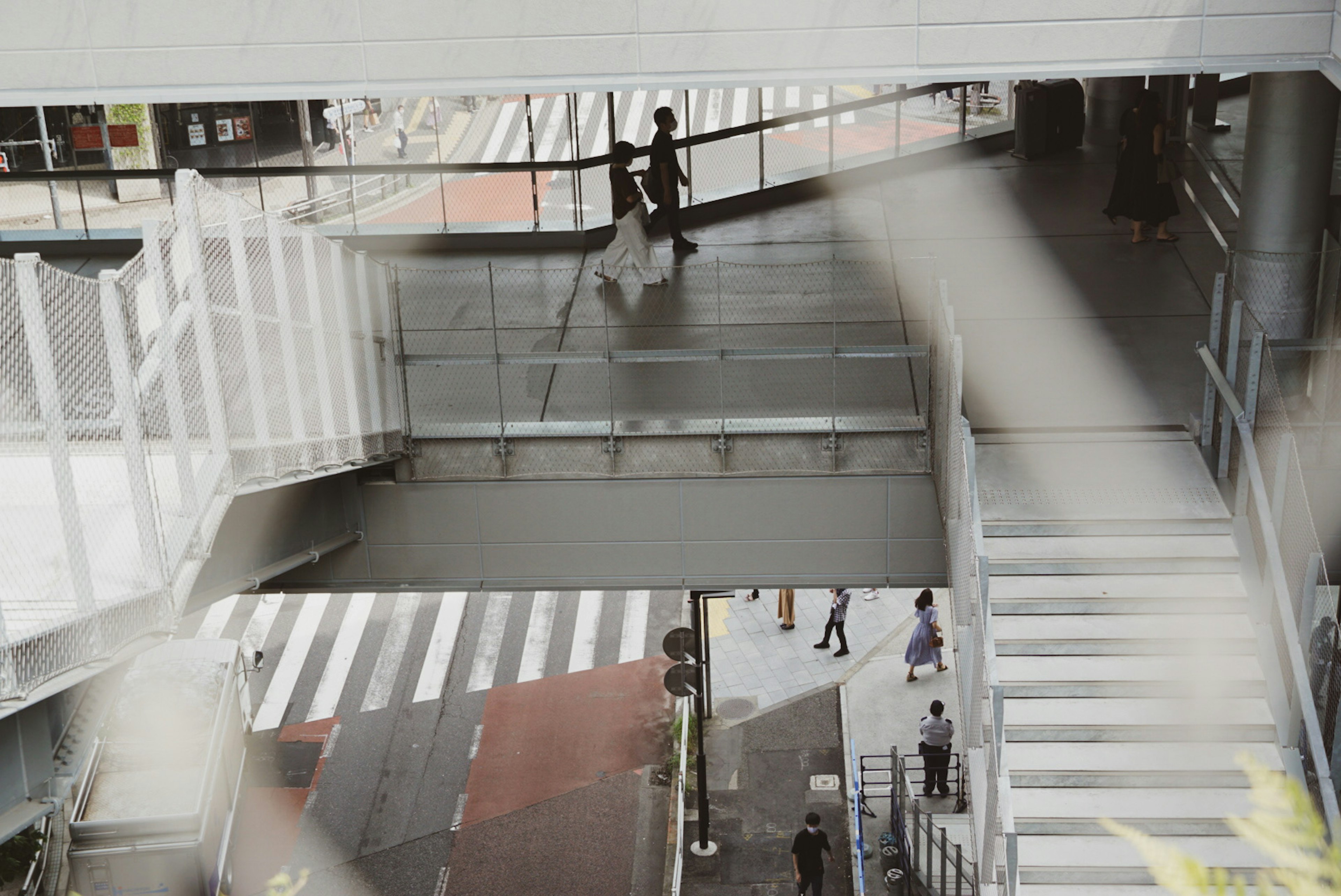 Pedestrians crossing a street with an overhead walkway