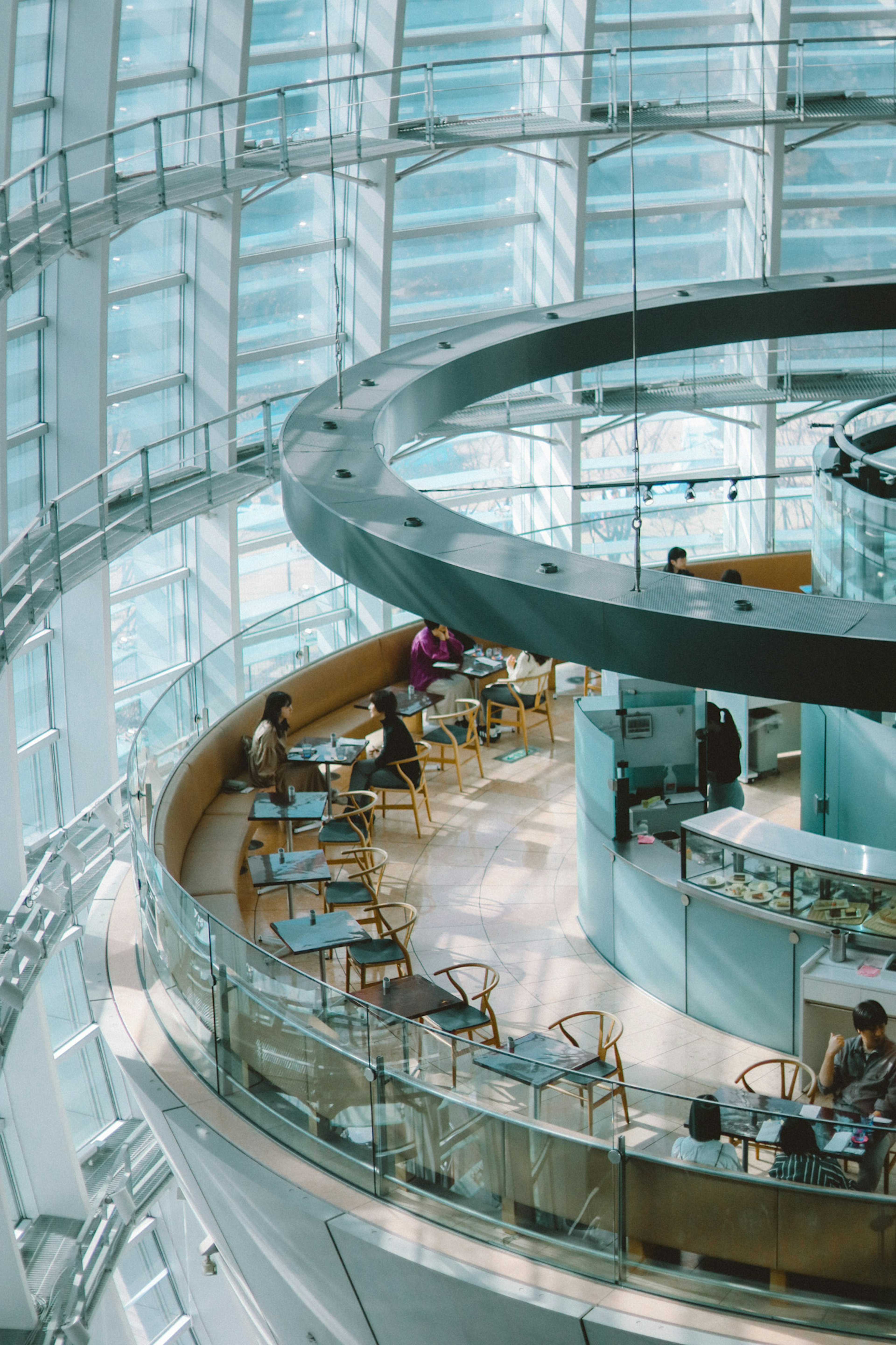 Cafetería moderna con paredes de vidrio y área de comedor circular