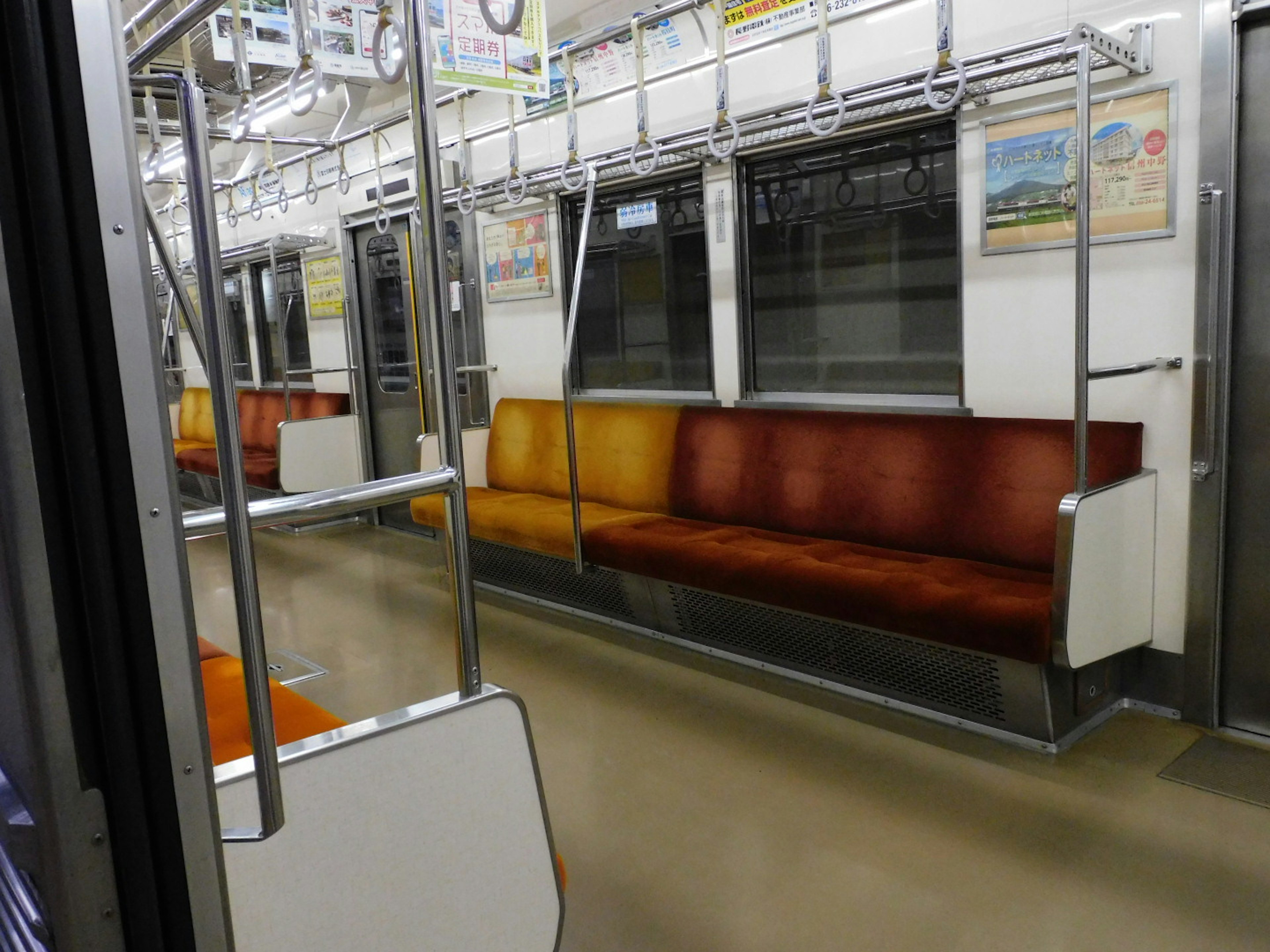 Interior of an empty subway train featuring orange and brown seats