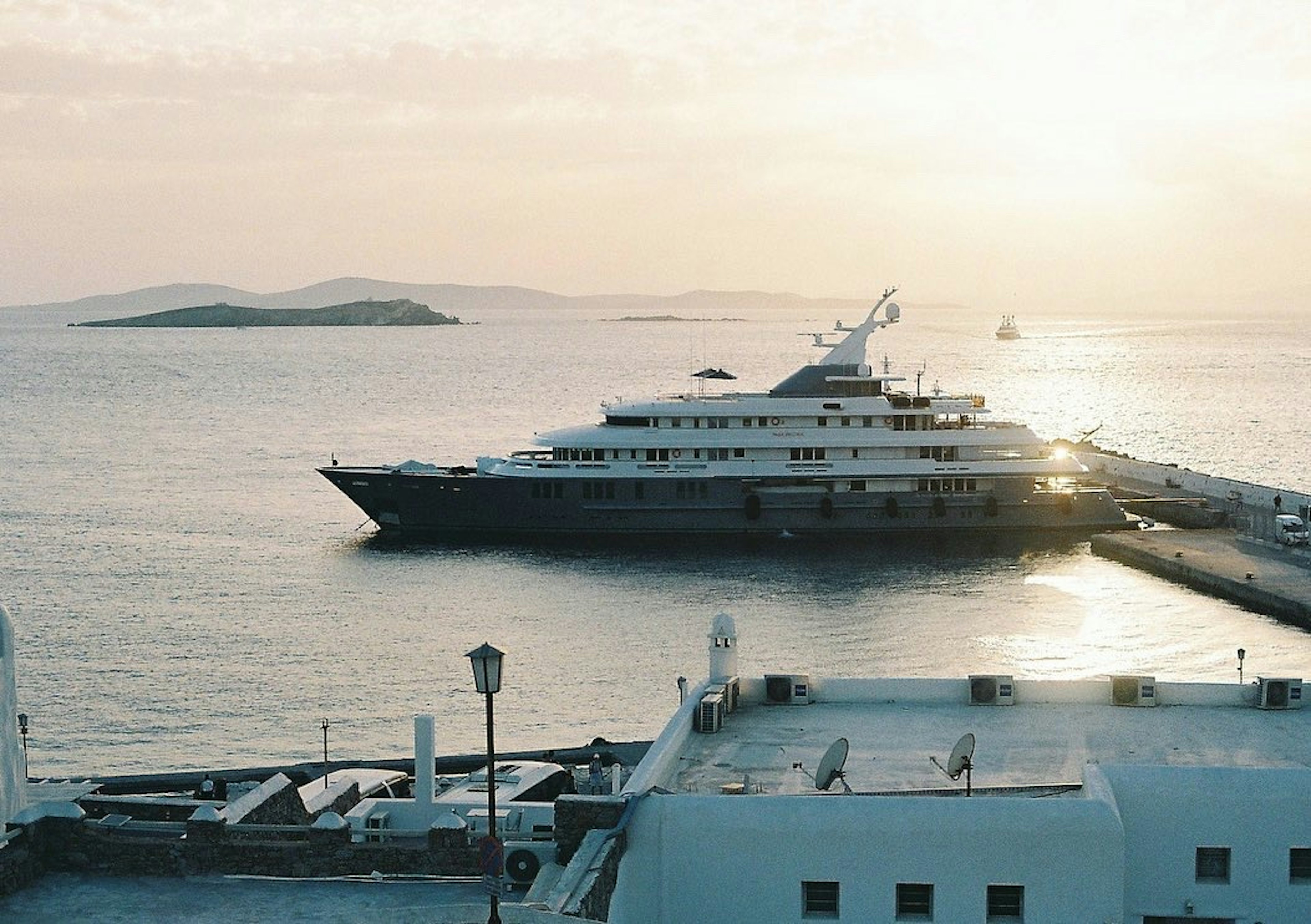 A luxurious cruise ship docked at a harbor with a sunset backdrop